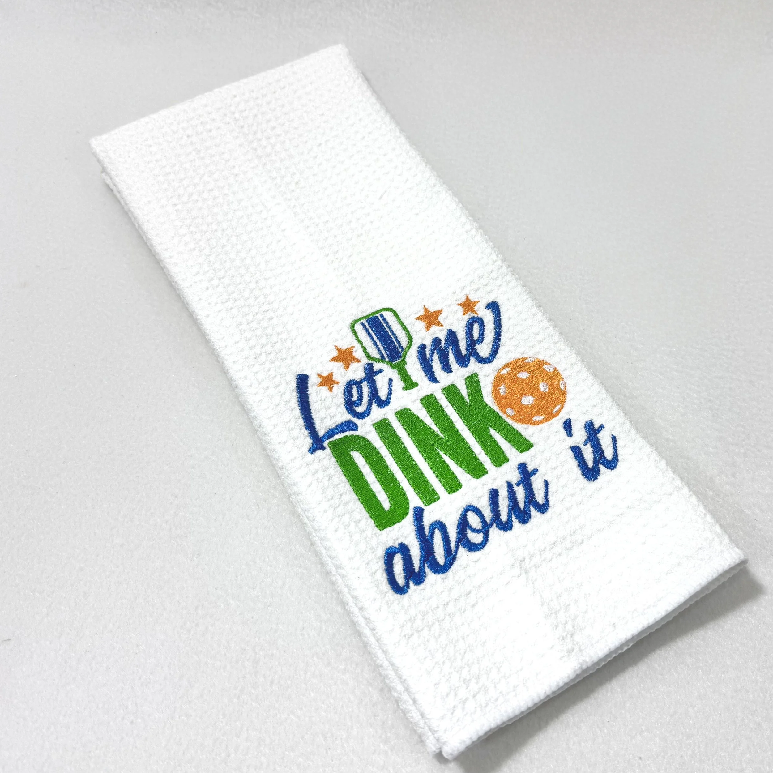 Let Me DINK About It embroidered microfiber kitchen and hand towel folded on white background, showing colorful pickleball design