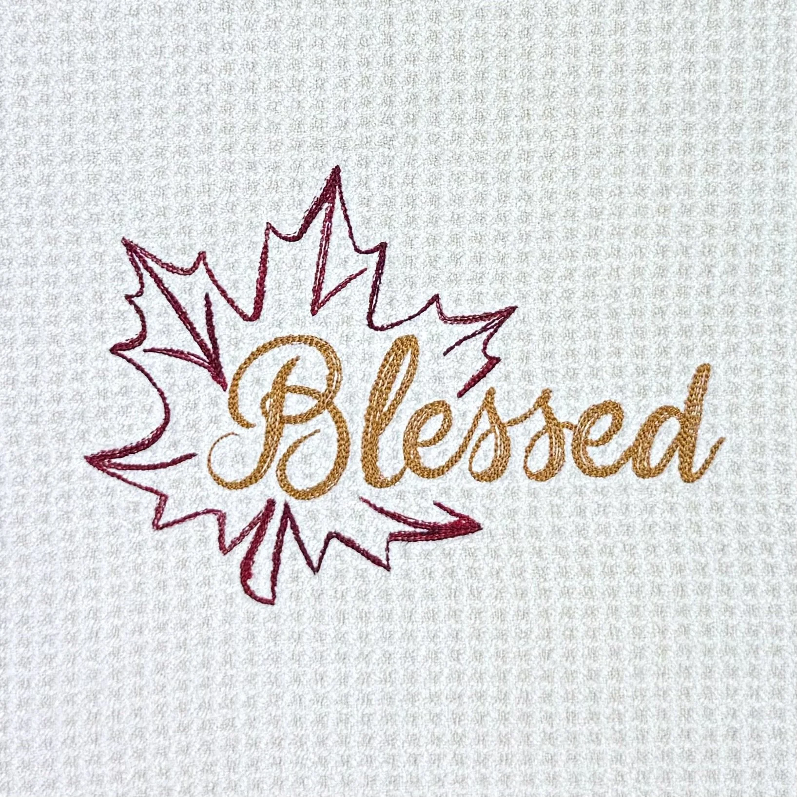 Close-up of Blessed Leaf embroidery on microfiber kitchen and hand towel, showing detailed stitching and towel texture