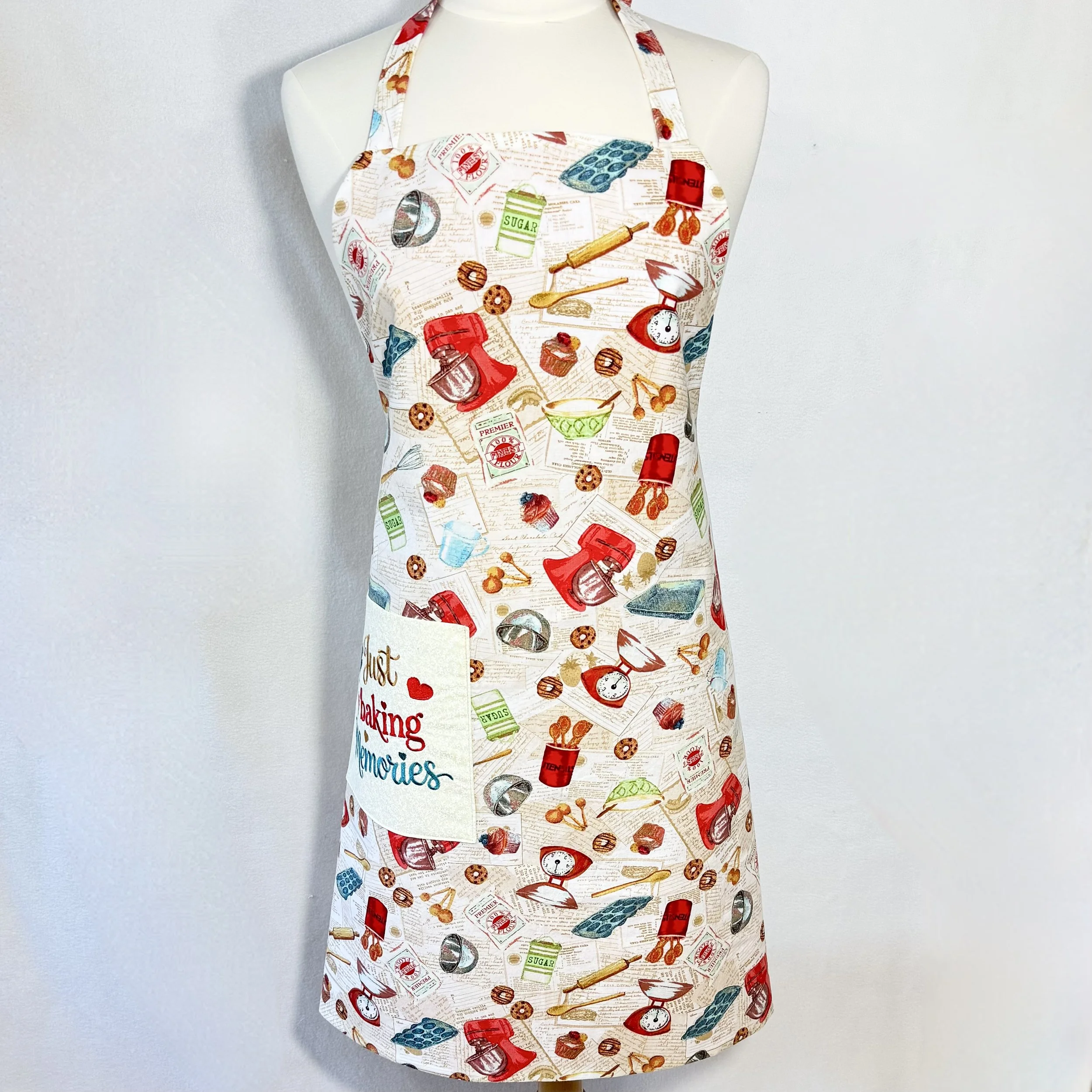Front view apron with vintage-inspired baking print in warm red and teal tones