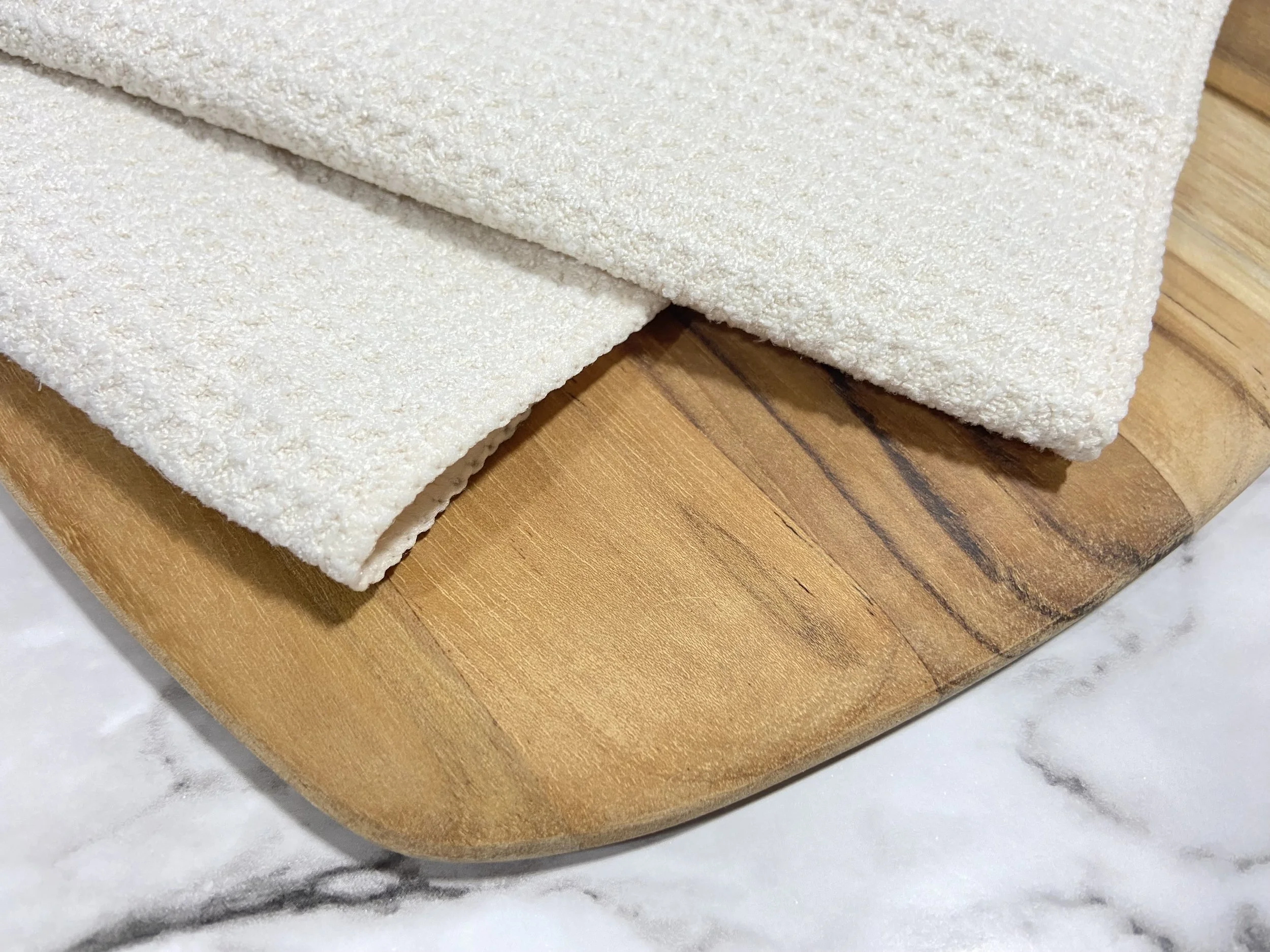 Close-up of cream microfiber kitchen and hand towel edge and waffle weave texture, showing high-quality material