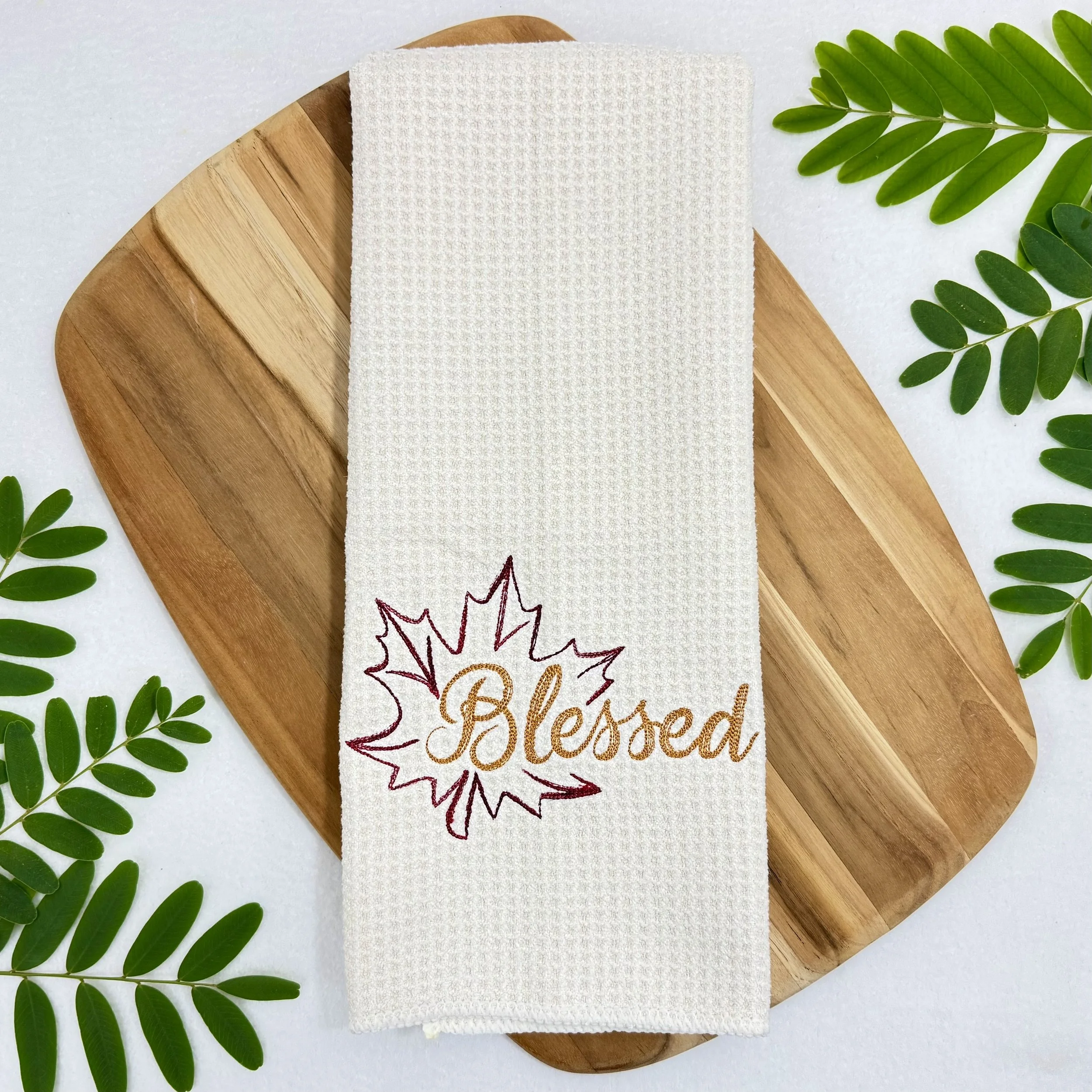 Blessed Leaf embroidered microfiber kitchen and hand towel flat lay with greenery and a cutting board