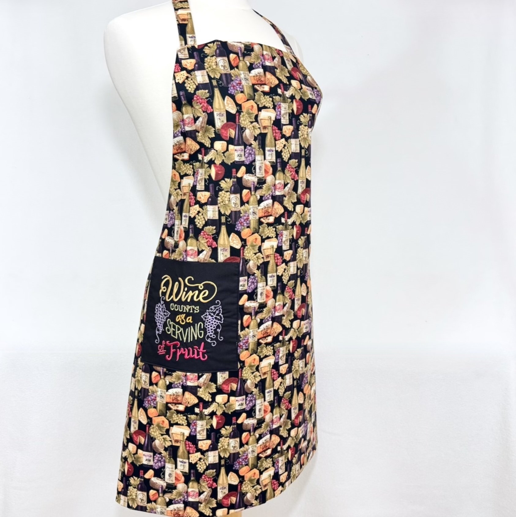 Wine, grapes, and cheese adult apron on a mannequin, showing the embroidered pocket and adjustable ties