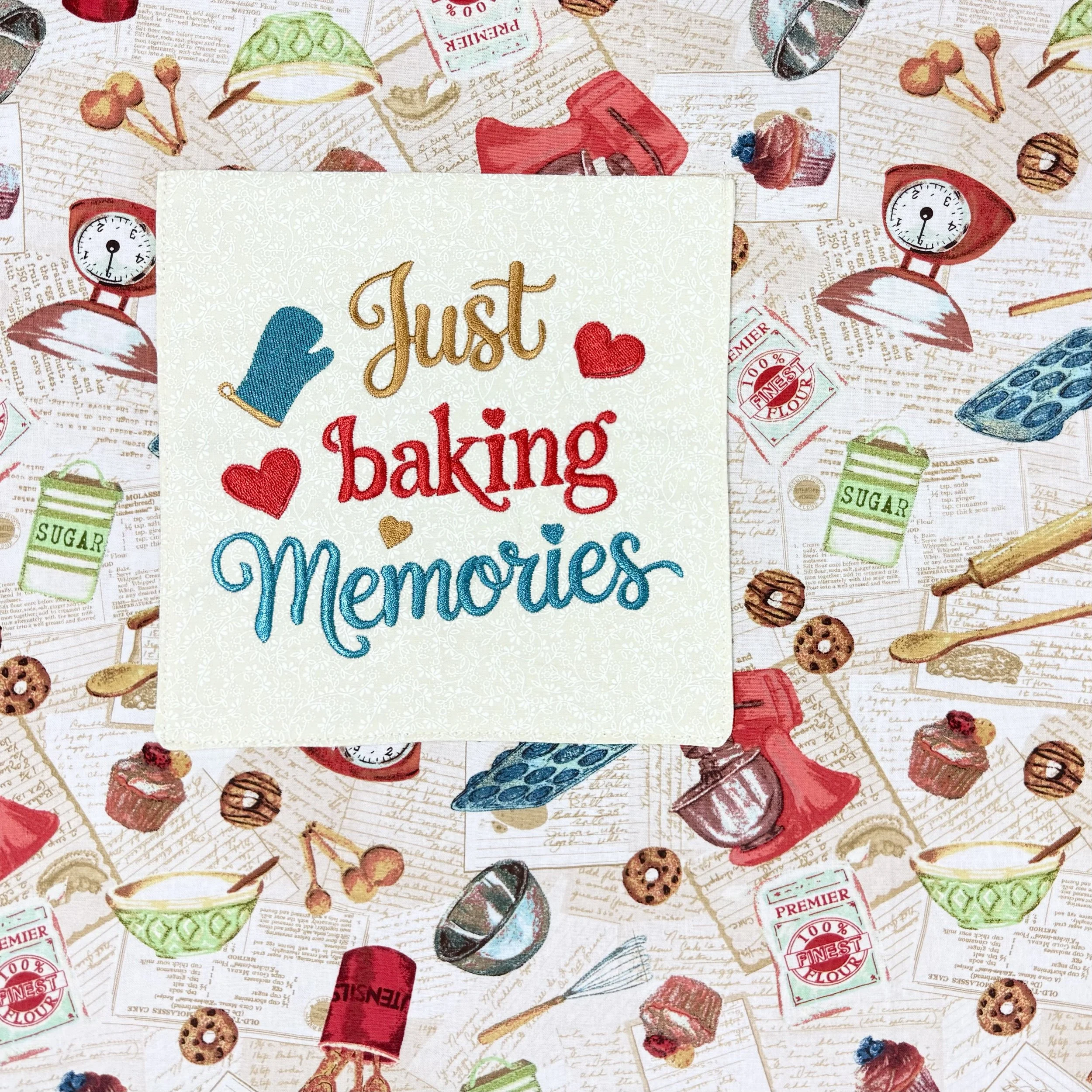 Close-up of embroidered “Just Baking Memories” pocket framed with heart accents and a baking mitt