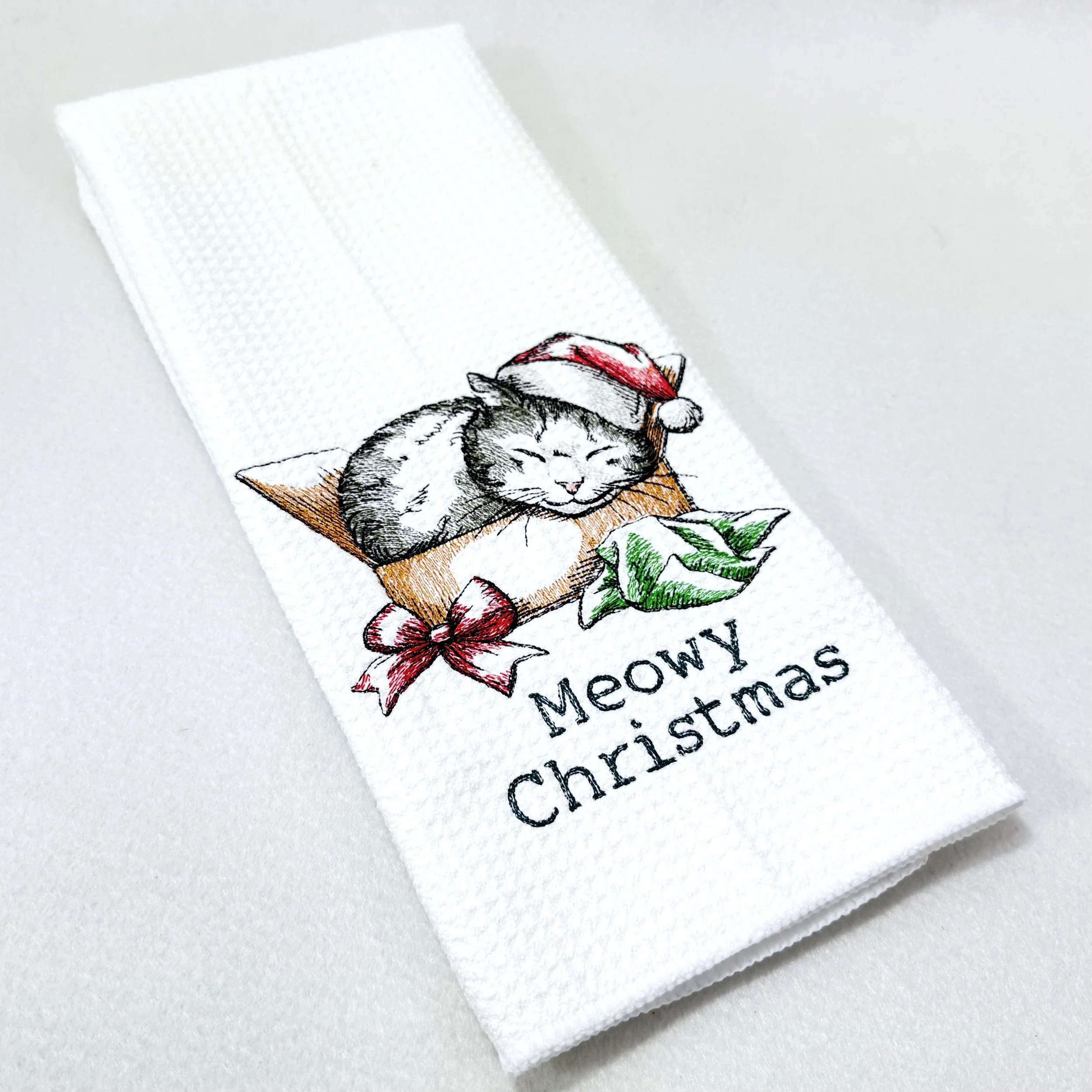 Meowy Christmas Present embroidered microfiber kitchen and hand Christmas towel folded on white background, showing design and texture
