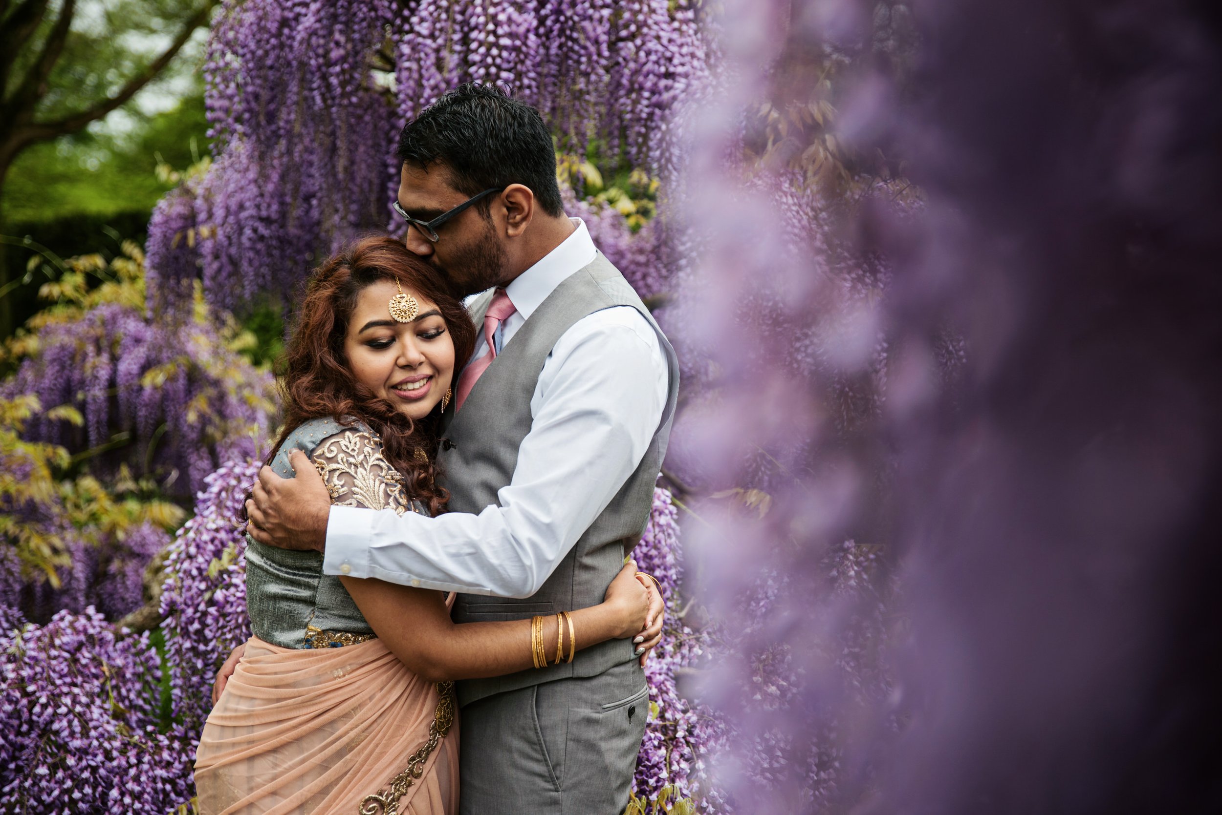 Couple hugging in a garden surrounded by purple flowers.