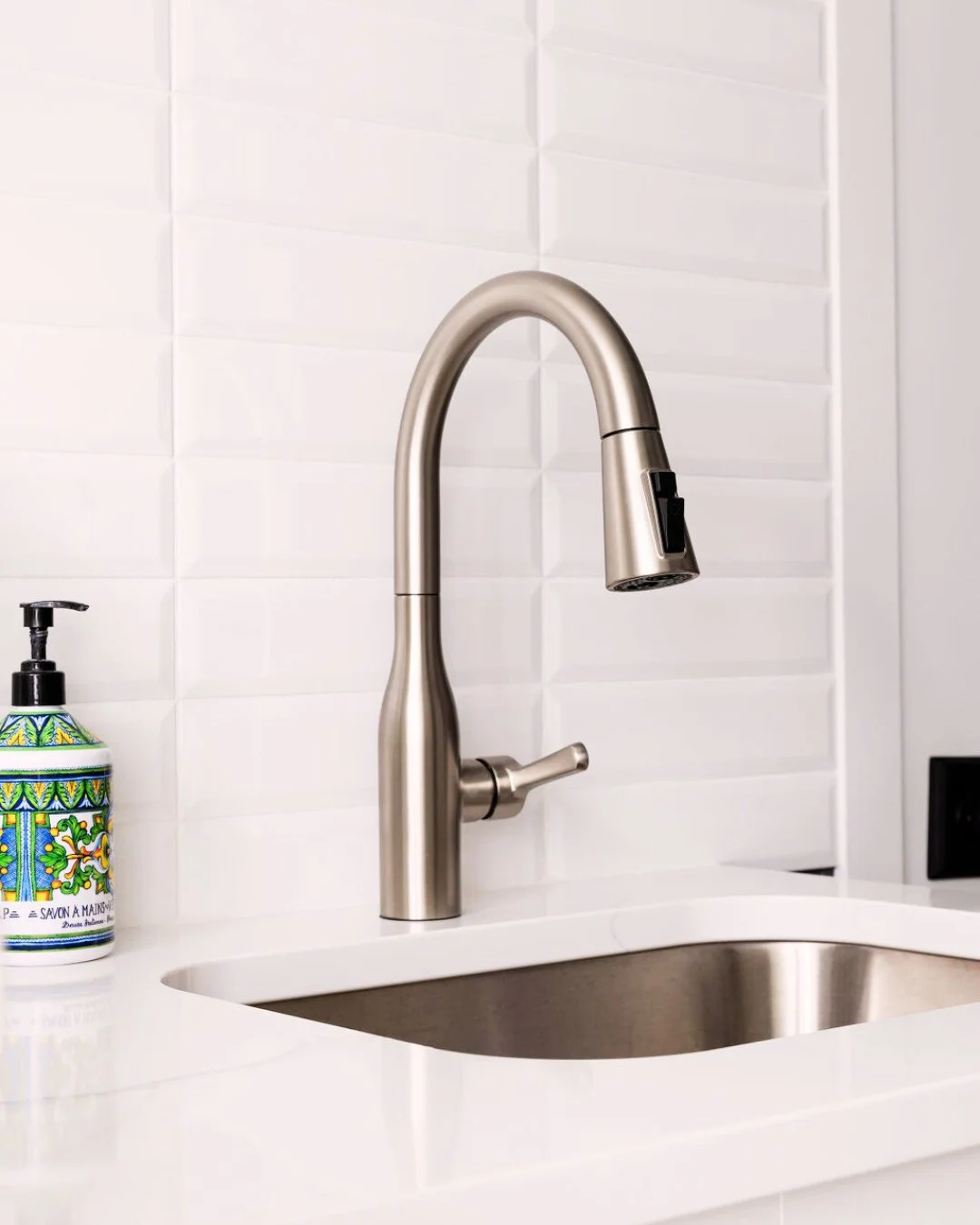 Simple upgrades? Big impact.⁠
⁠
This sleek pull-down faucet pairs perfectly with dimensional white tile and quartz counters, proving that thoughtful details can elevate even the most practical spaces.