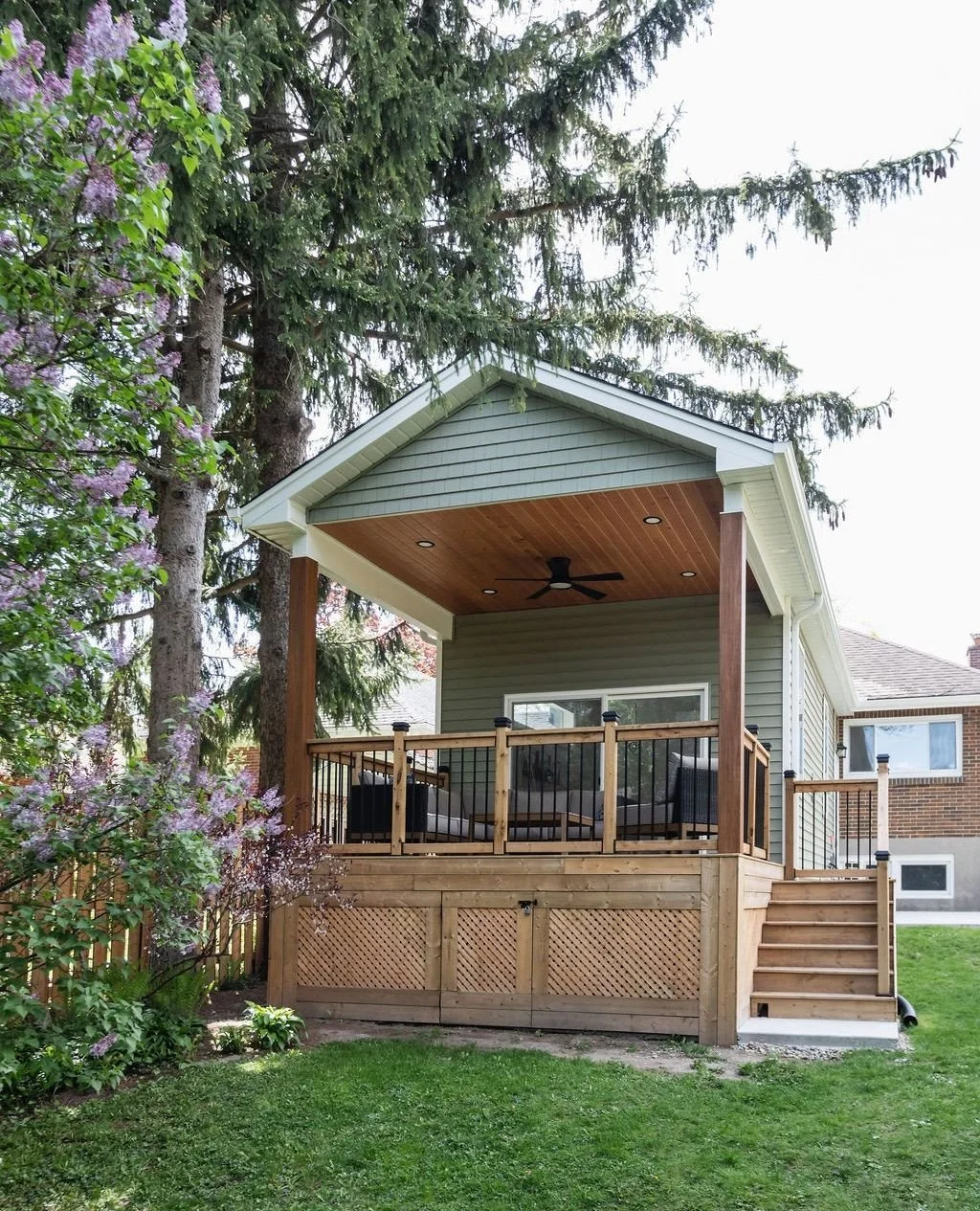 This covered porch might be our favourite part of the Victoria project.⁠
⁠
Tucked beneath mature trees and a stunning lilac bush, this indoor/outdoor living room is a place to slow down, enjoy a morning coffee, or spend an evening with family and fri