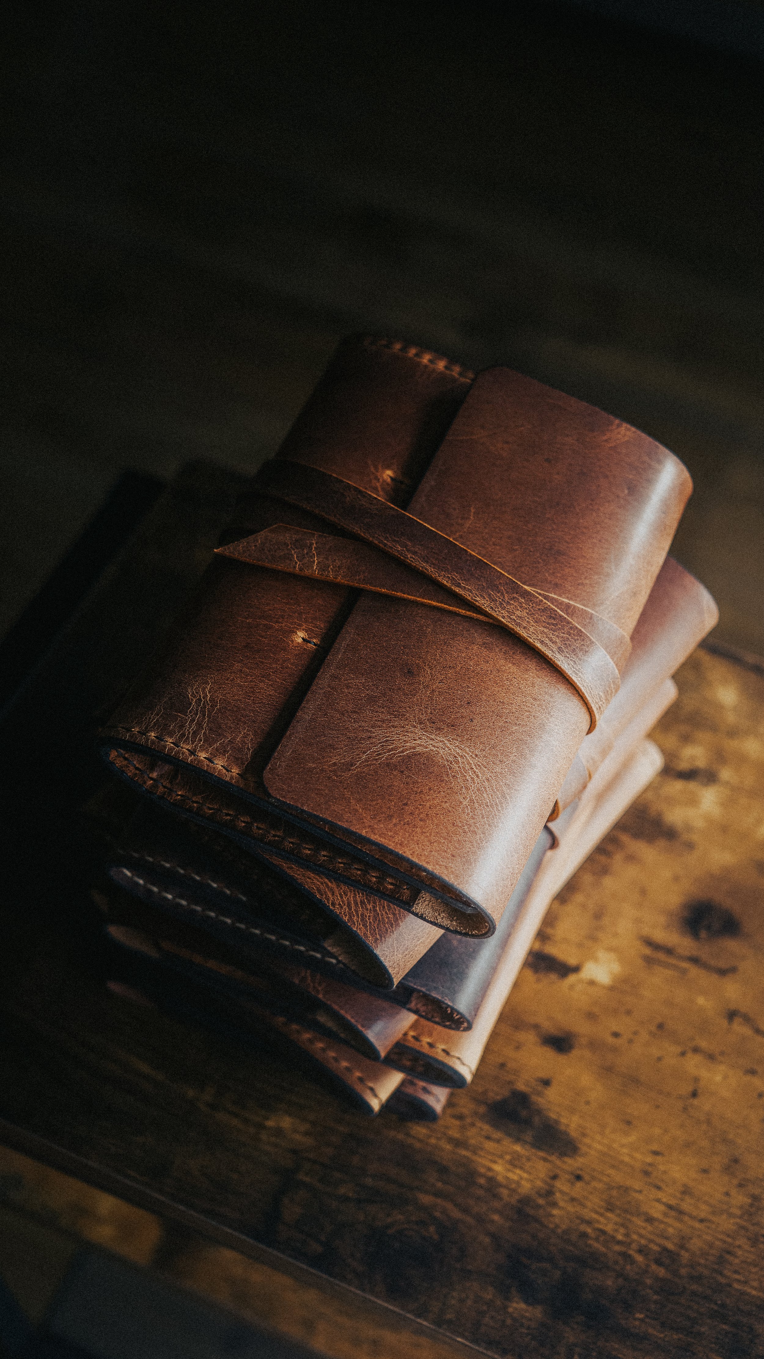 Stack of leather-bound journals or notebooks on a wooden surface.