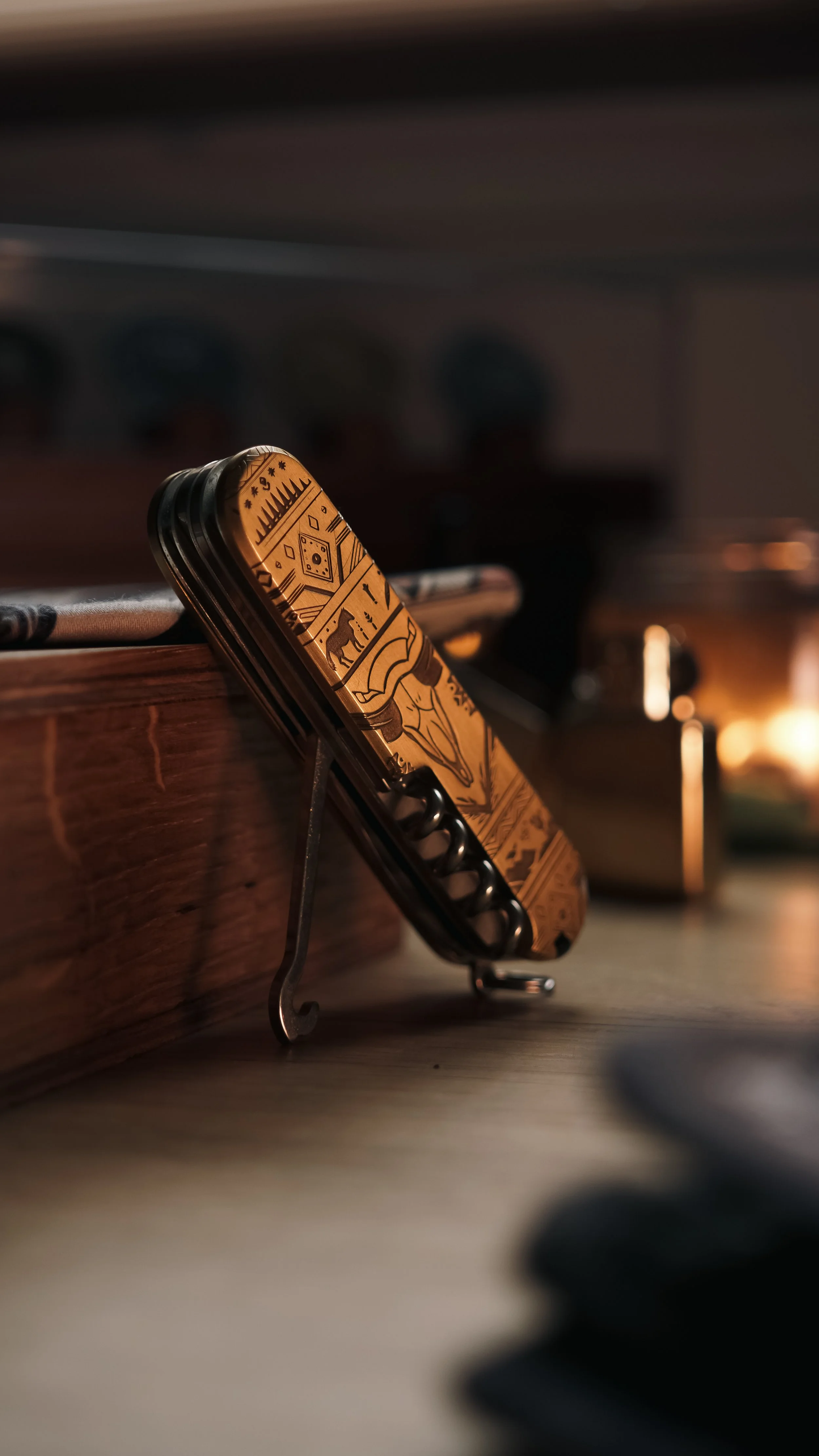 A multi-tool knife with a gold-colored handle and various tools extended, resting on a wooden surface.