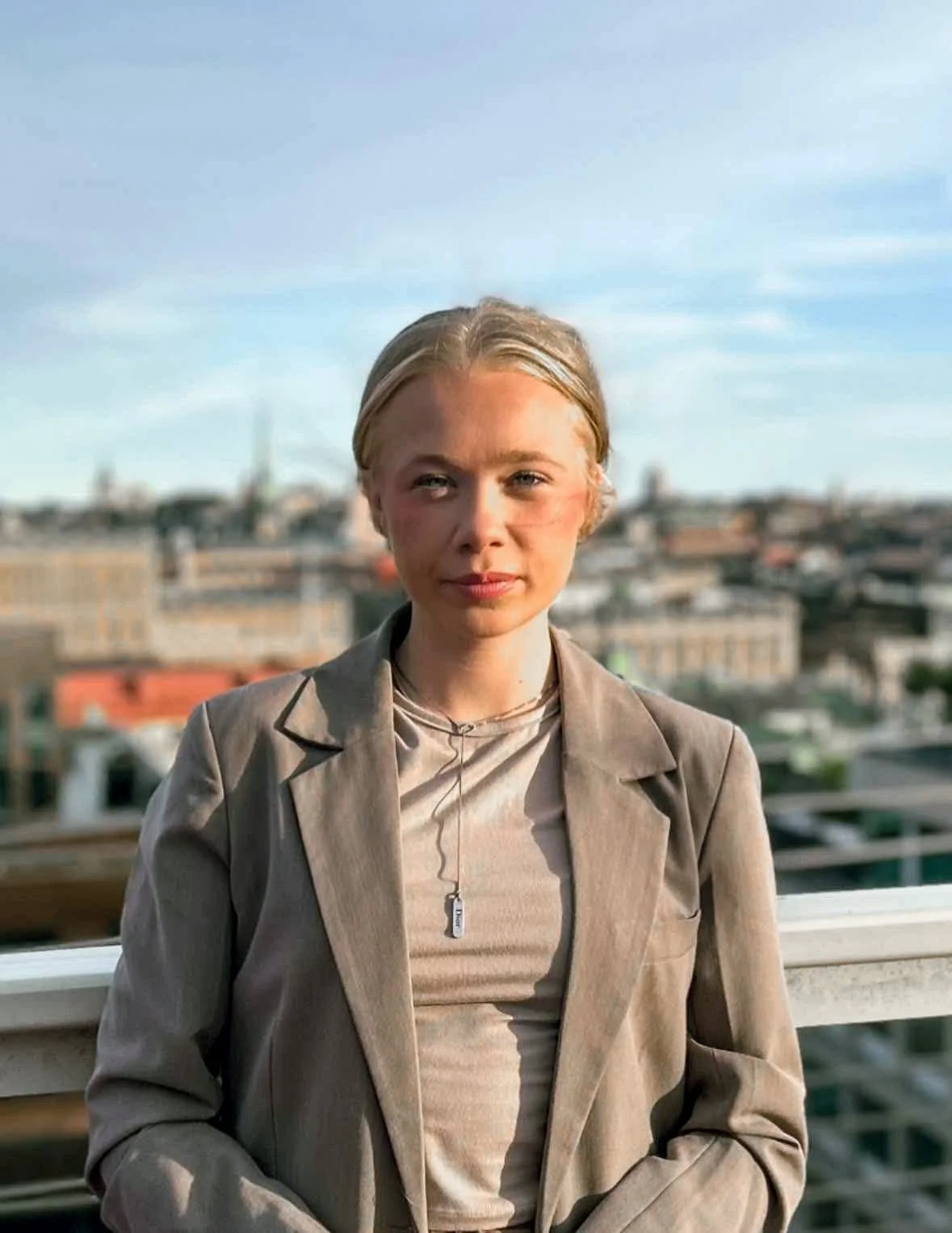 Rakel Friberg i en grå kavaj med uppsatt hår utomhus i skymning.