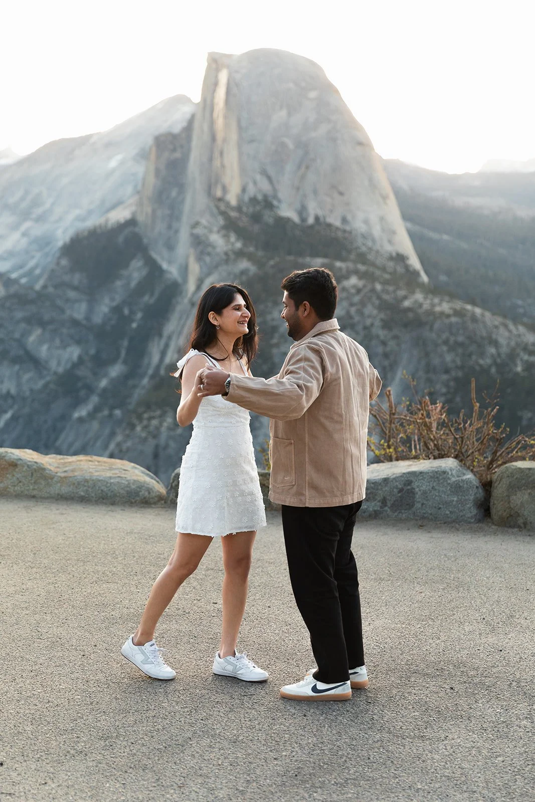 candid engagement photo of couple dancing on yosemite trail at glacier point