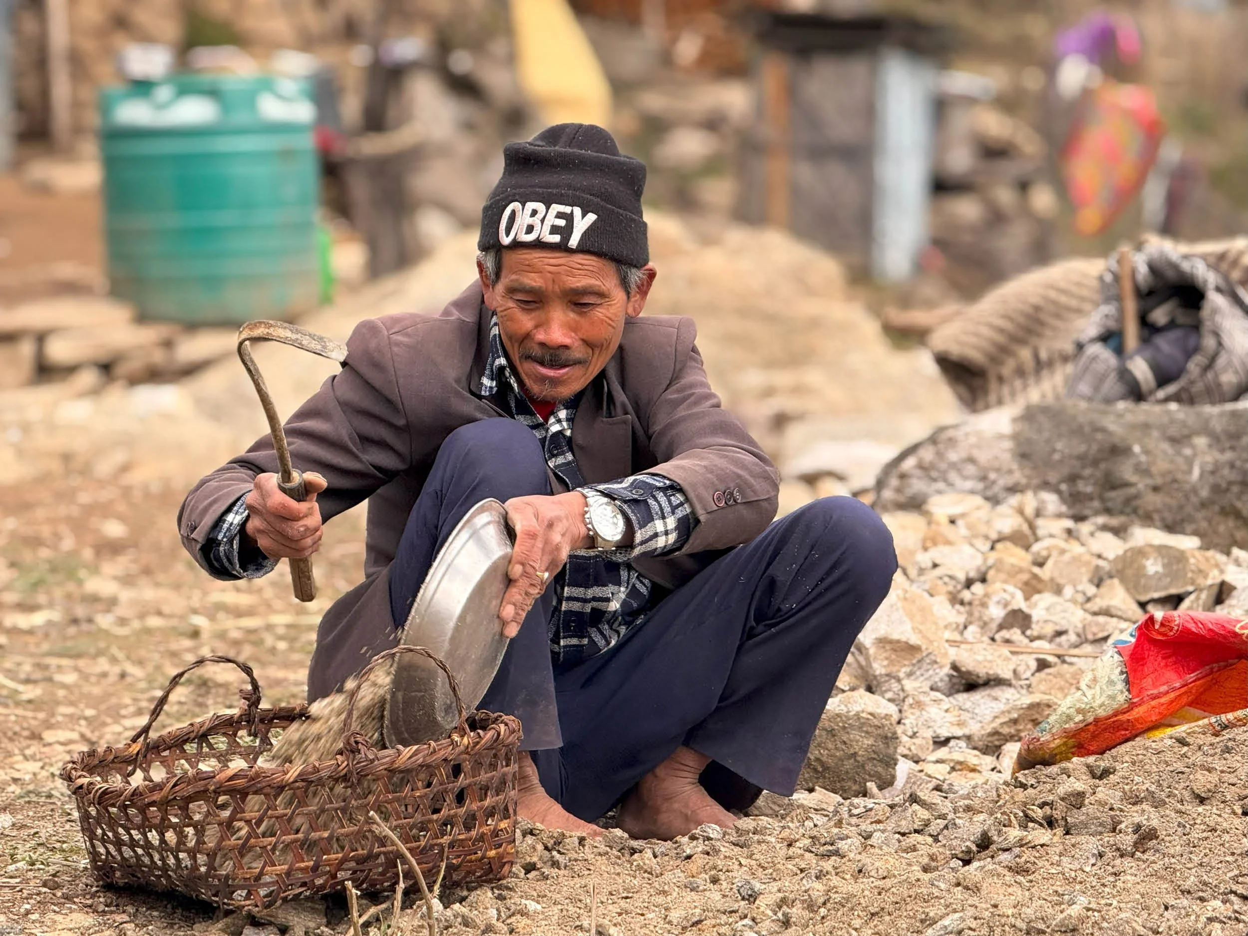 A village elder in Ekuwa collects stone in a basket to be used for the construction of the Health Post.