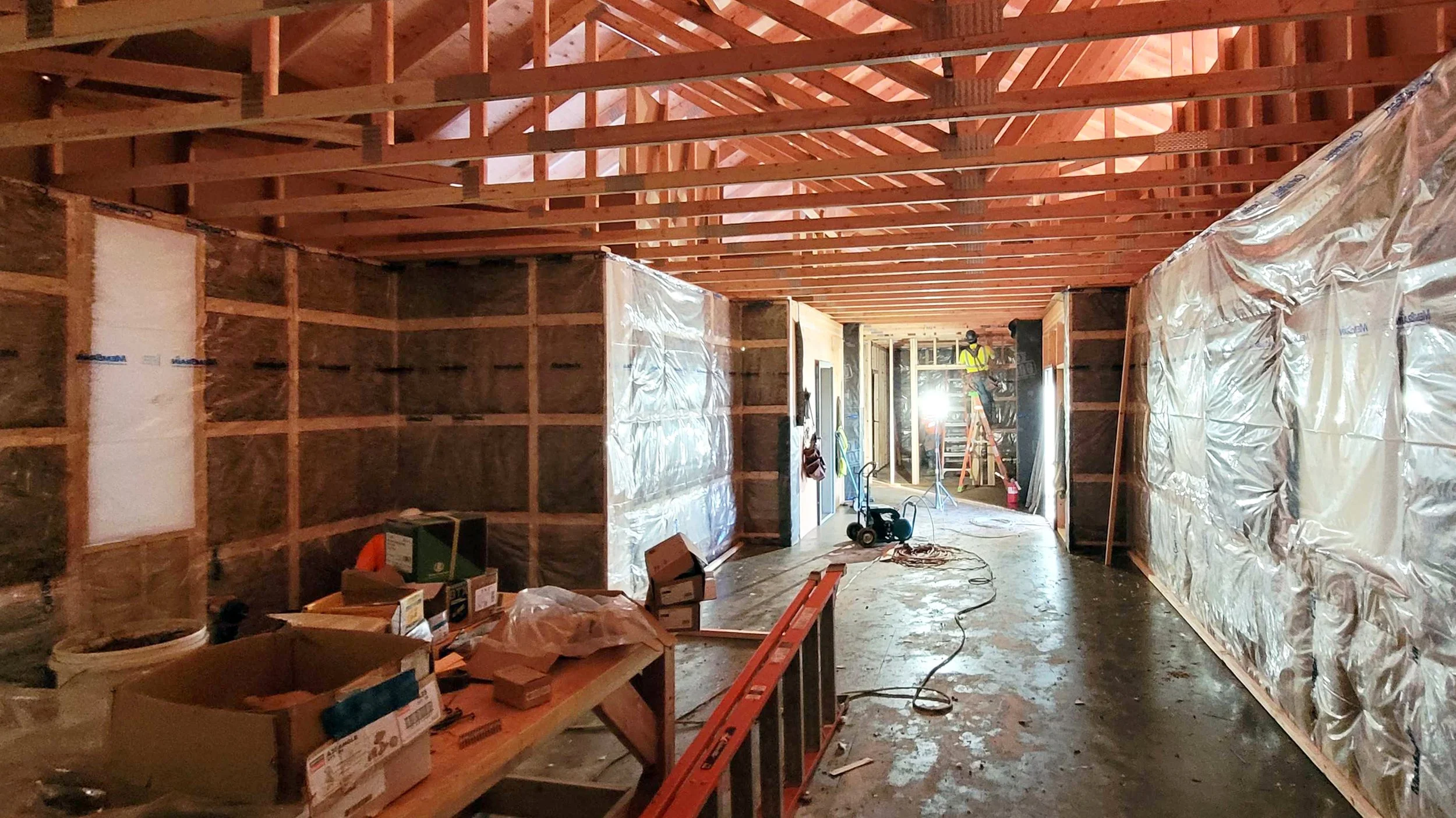 The interior of the Welcome House during construction showing exposed straw panels and prefabricated roof trusses.