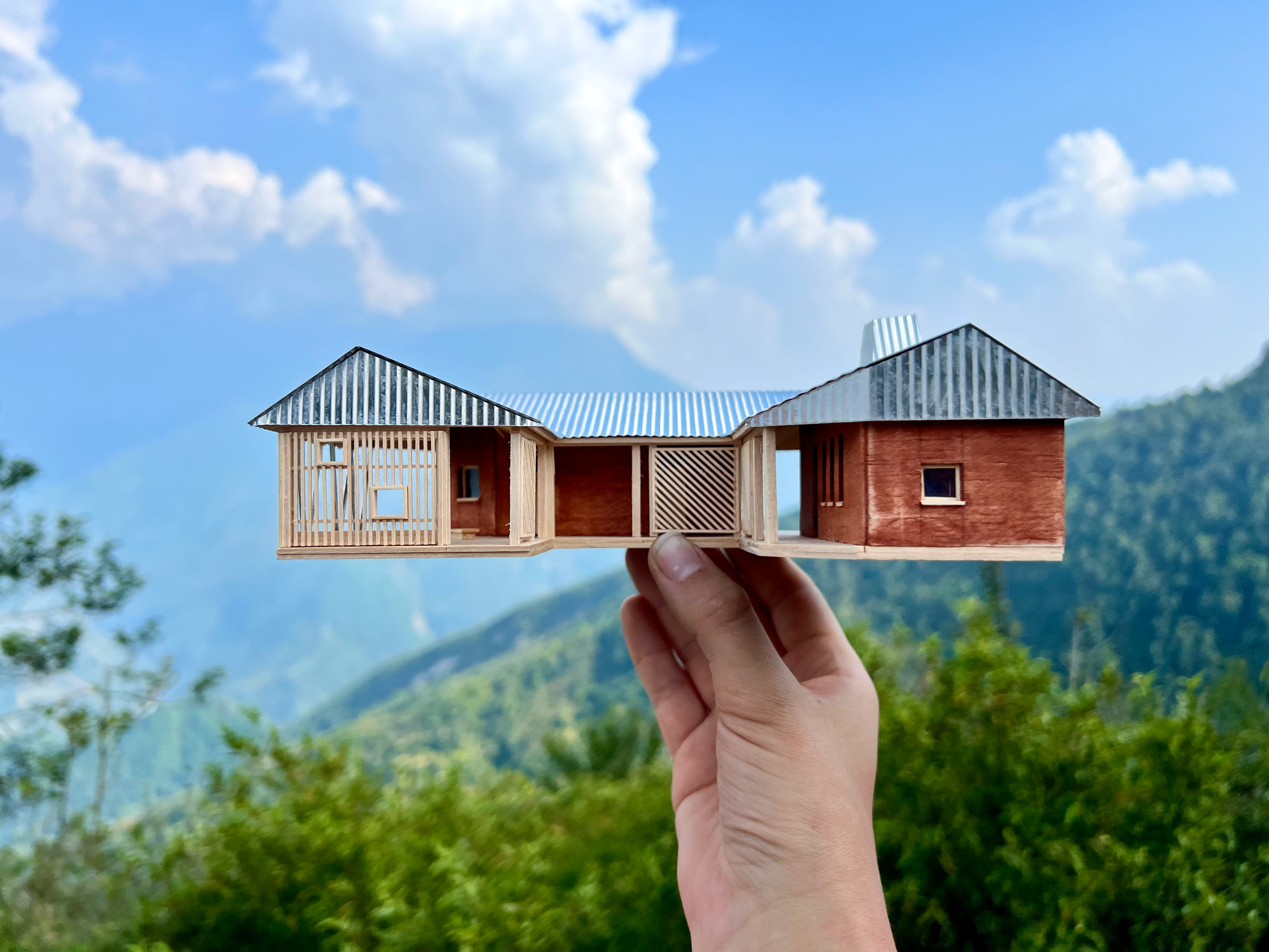 The model of the Ekuwa Health Post, held up against the hills and sky of rural Nepal.