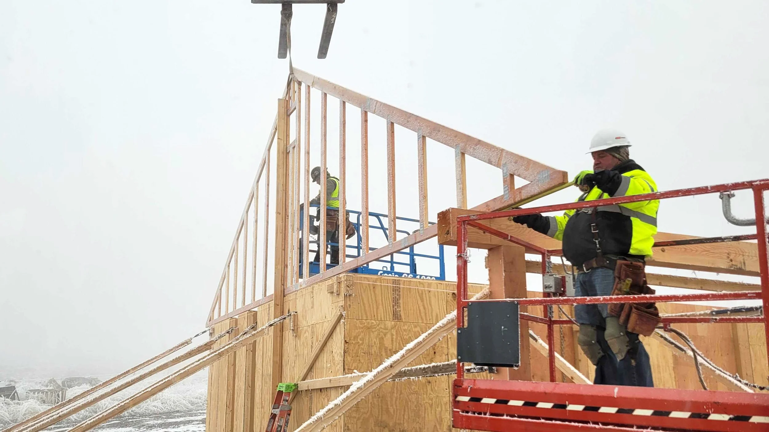 Construction workers erect the roof trusses of the Welcome House on a snowy morning in Montana.