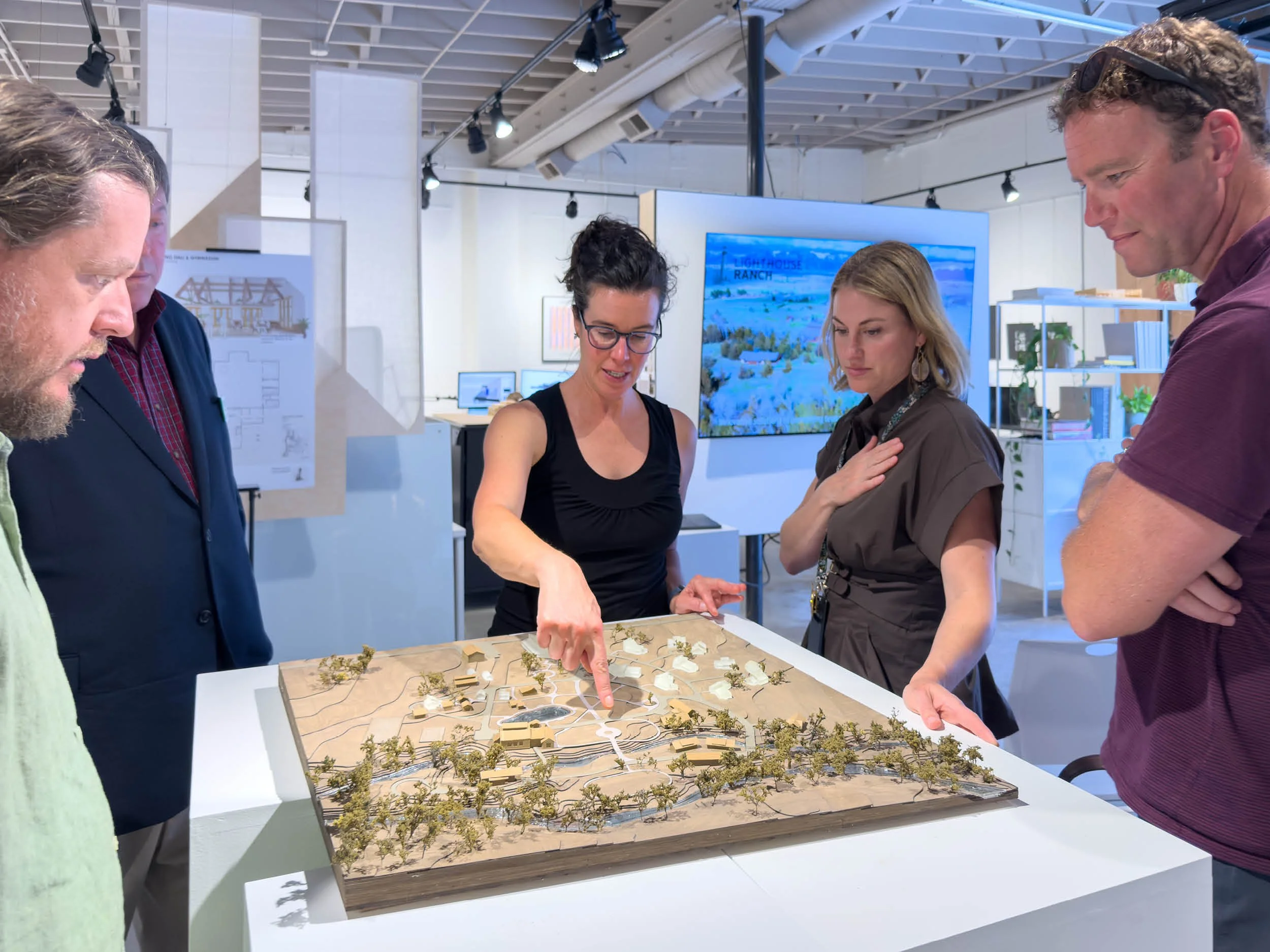 People gather around a large architectural site model of the Lighthouse Ranch in Montana.