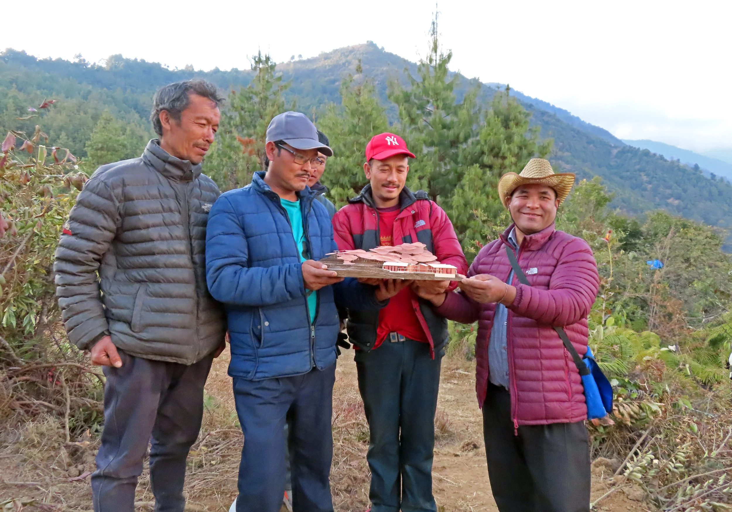 Villagers pose proudly with Building Bureau's model of the Helambu Hospital on site in Nepal.