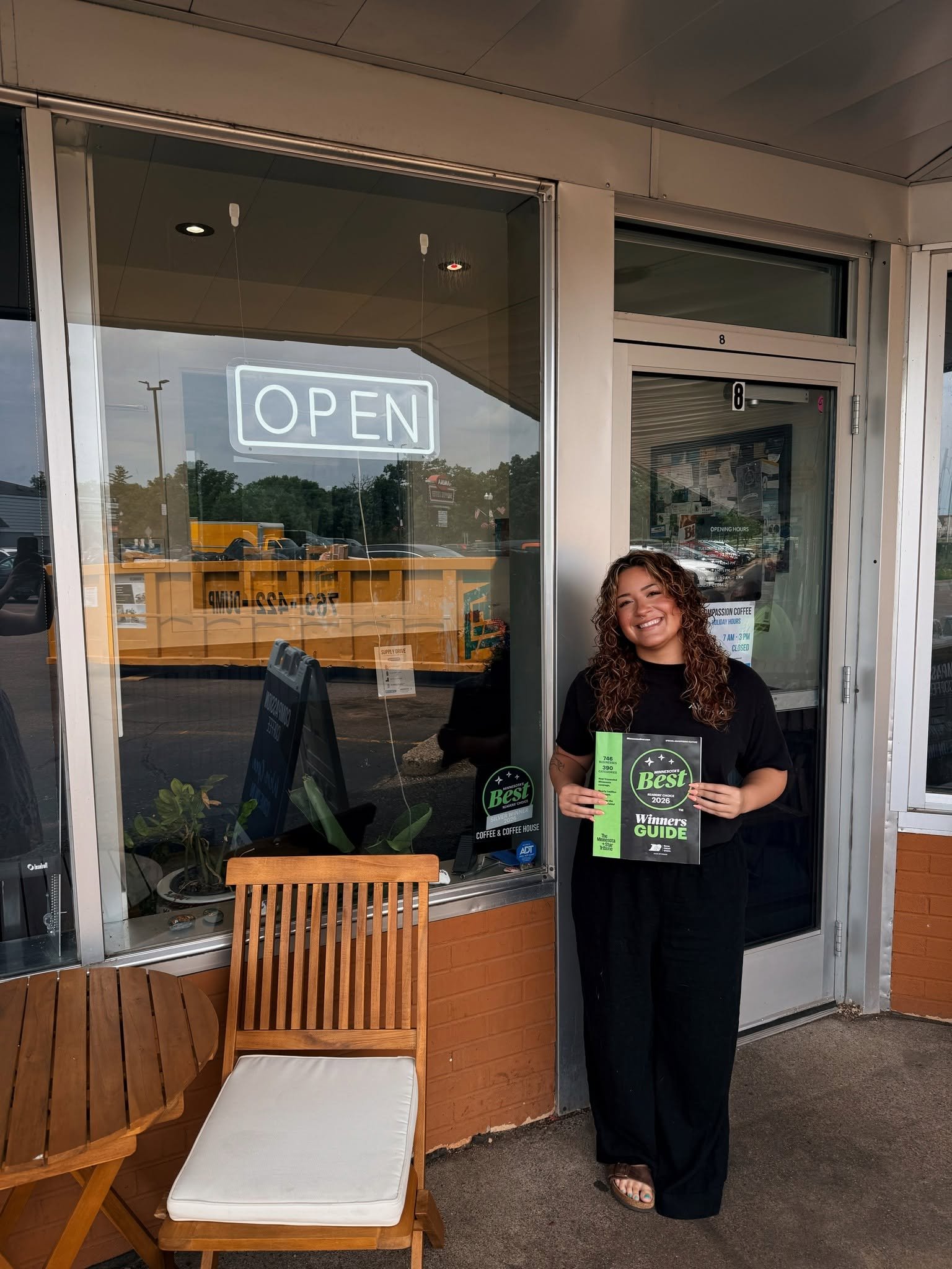A woman proudly holds the 2026 Star Tribune Minnesota Best magazine featuring Compassion Coffee, recognized as Second Place for Best Coffee and Best Coffeehouse in Anoka, Minnesota. This award highlights Compassion Coffee's handcrafted coffee, welcom