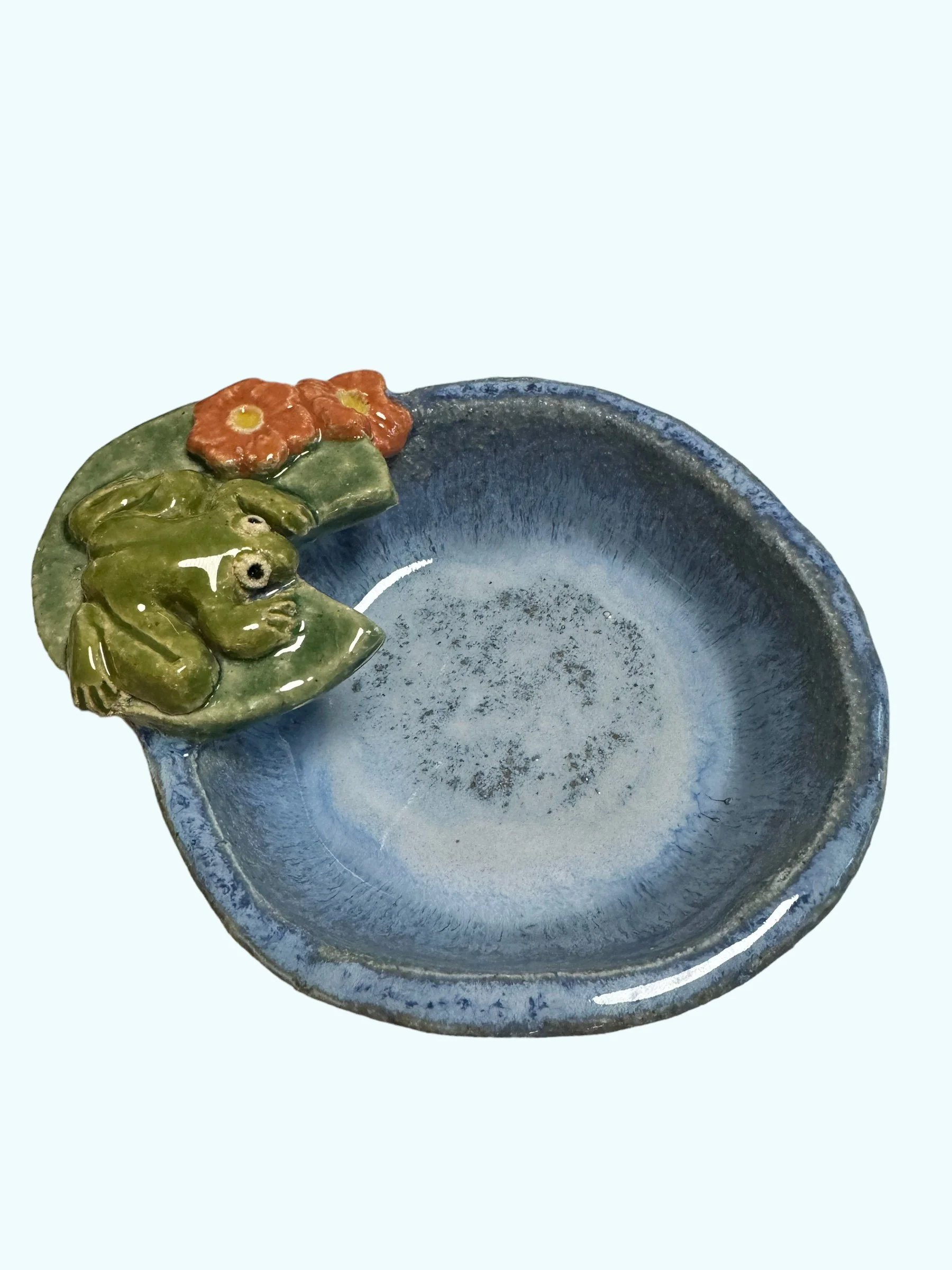 A ceramic bowl with a blue glaze and decorative frog and flower accents on the rim.