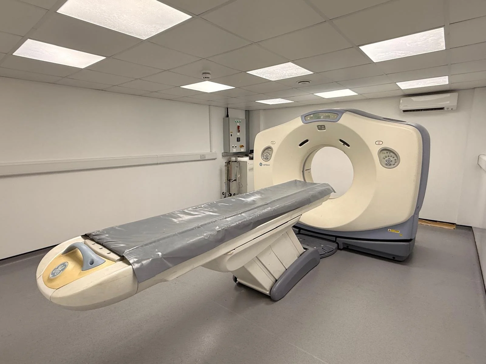 Medical imaging room with a large CT scanner and patient table.