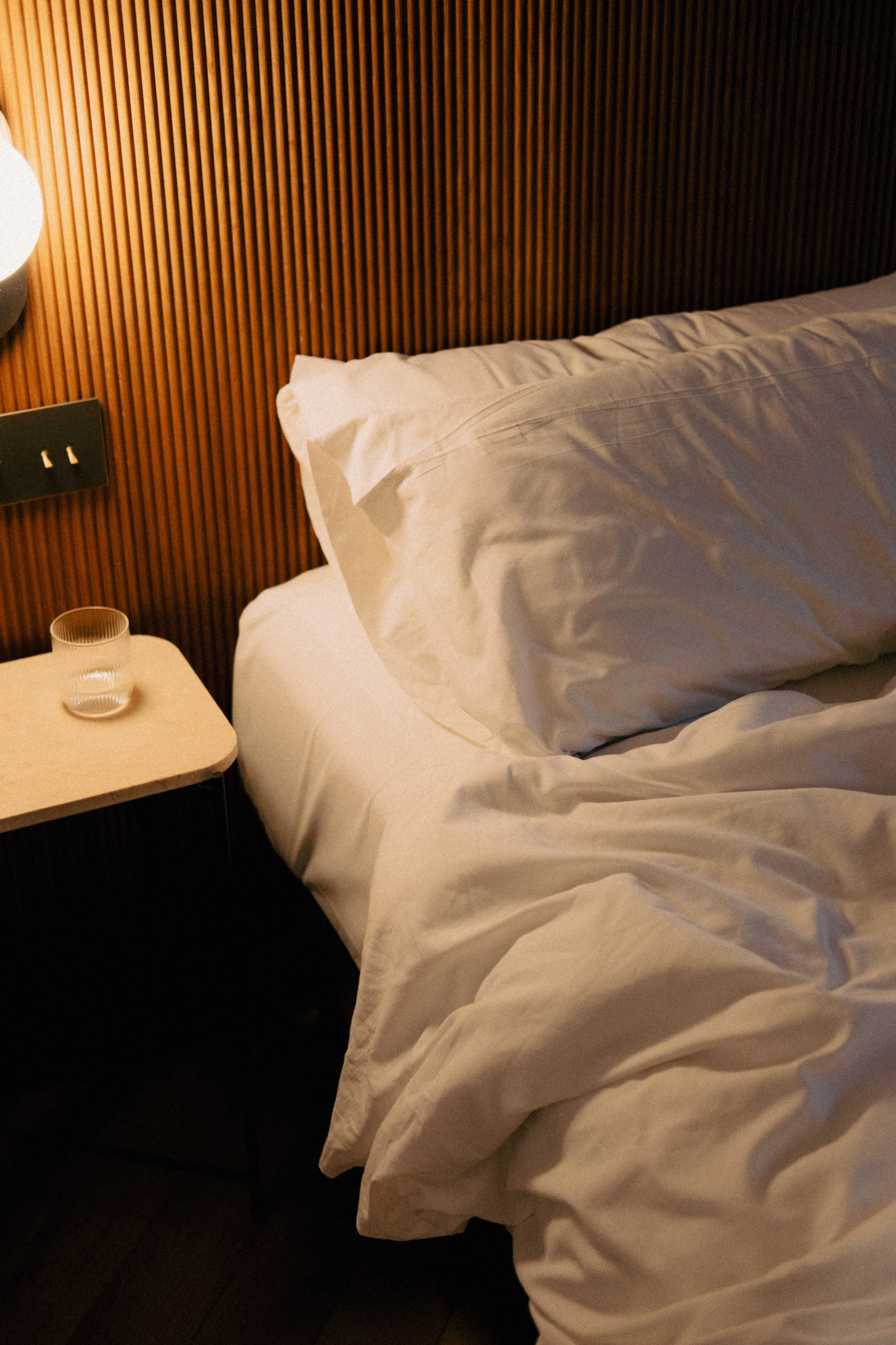 unmade luxurious bed with white cotton bedding