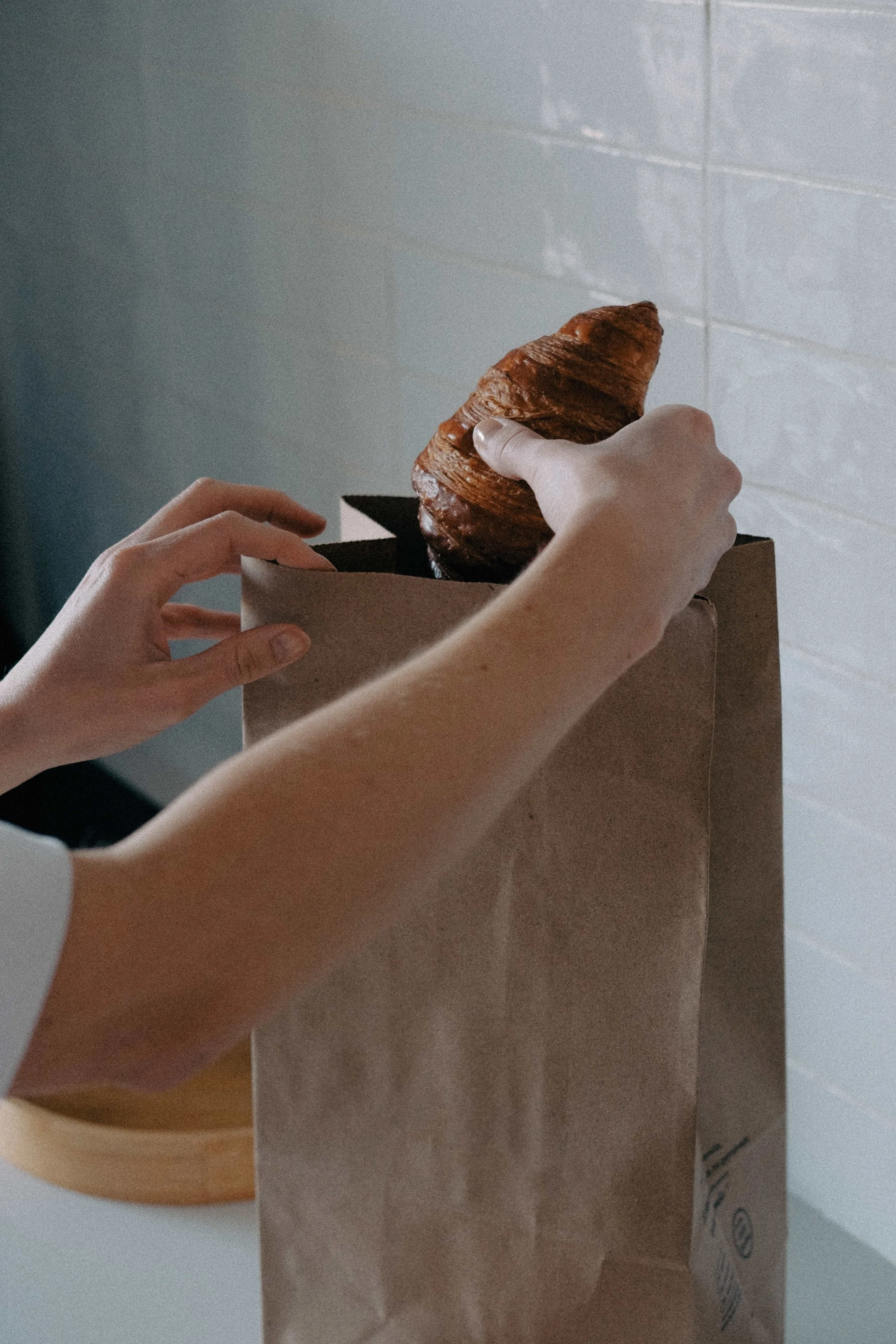 person taking a croissant out of a paper bag