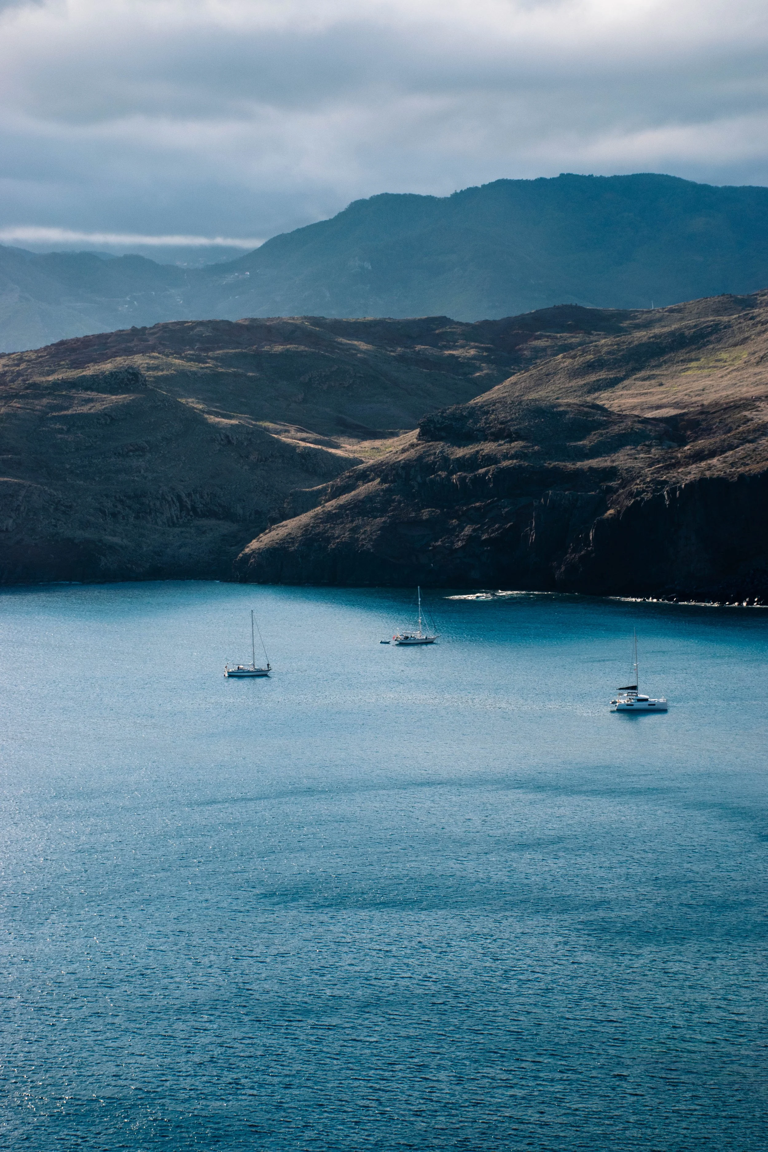 three boats on the see in front of magnificent cliffs