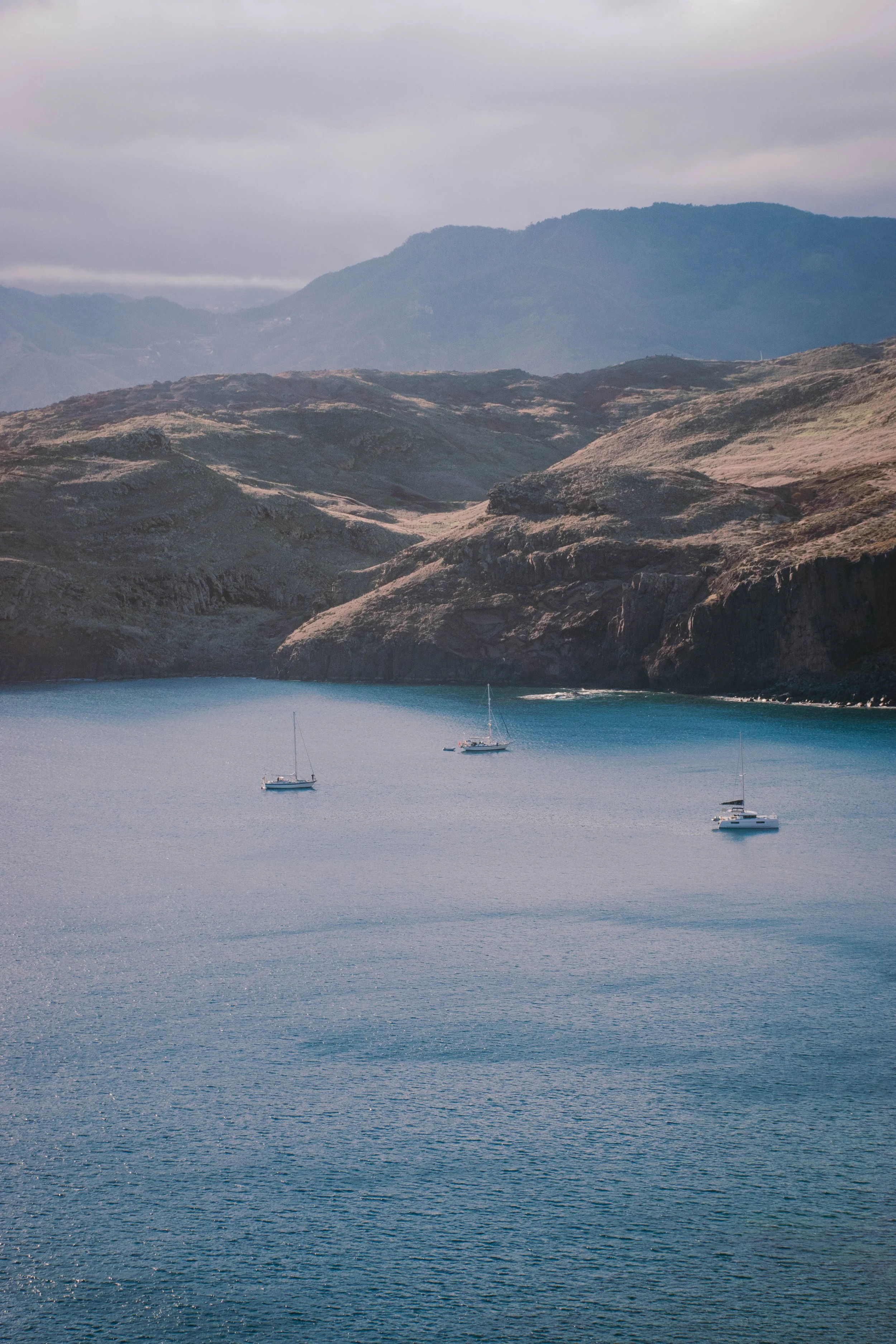three boats on the see in front of magnificent cliffs