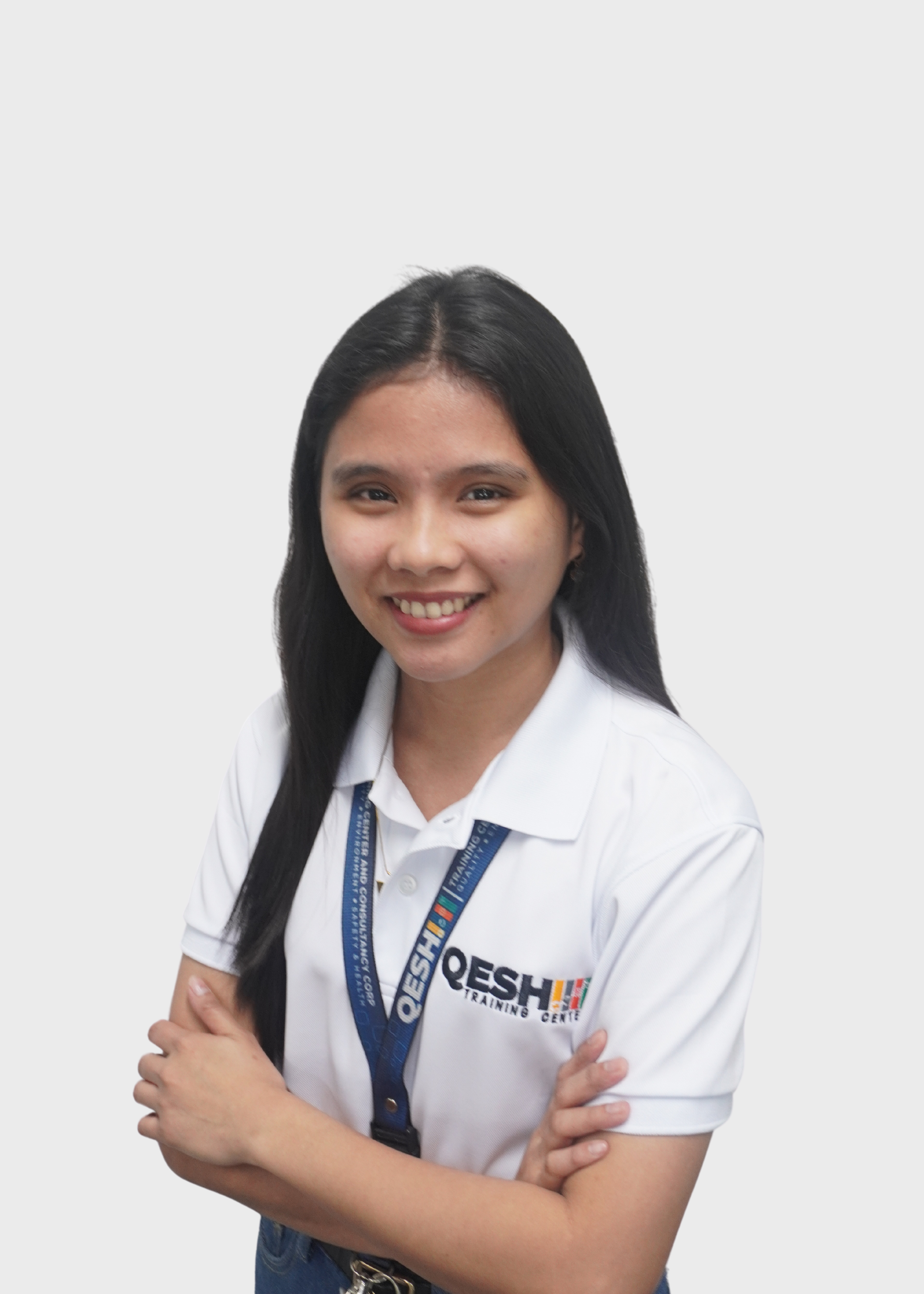 Smiling person in a QESH polo shirt with crossed arms.
