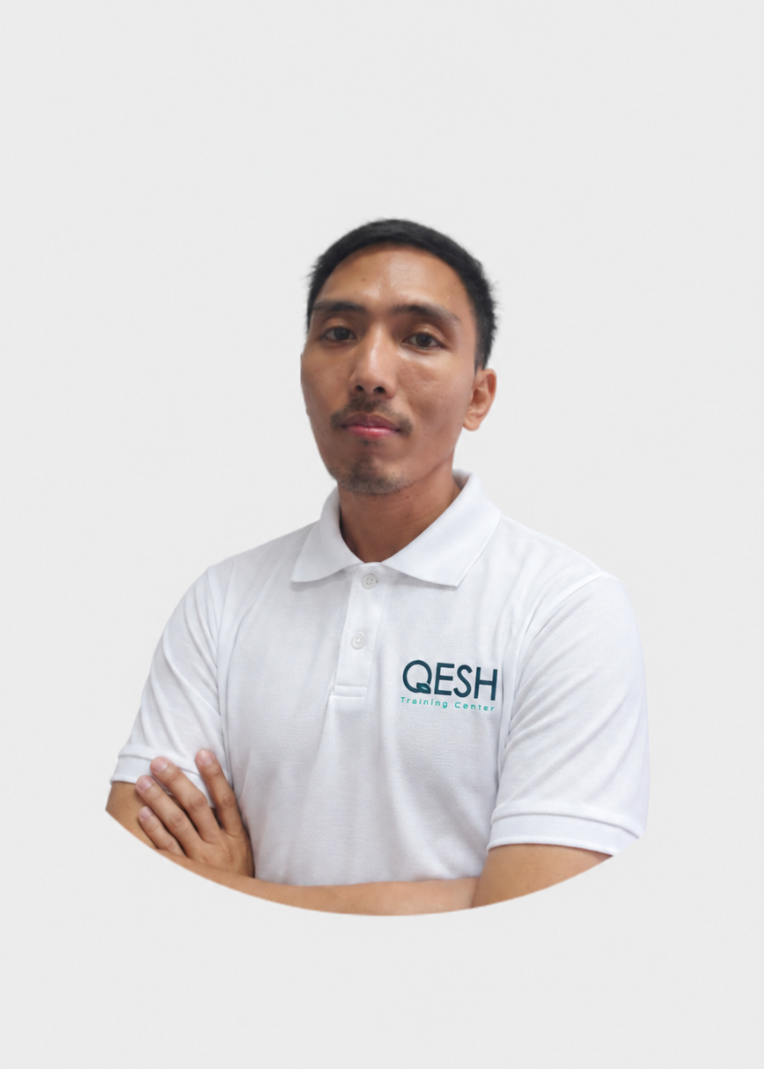 Man in a white and red polo shirt with 'QESH' logo, posing with arms crossed against a plain background.