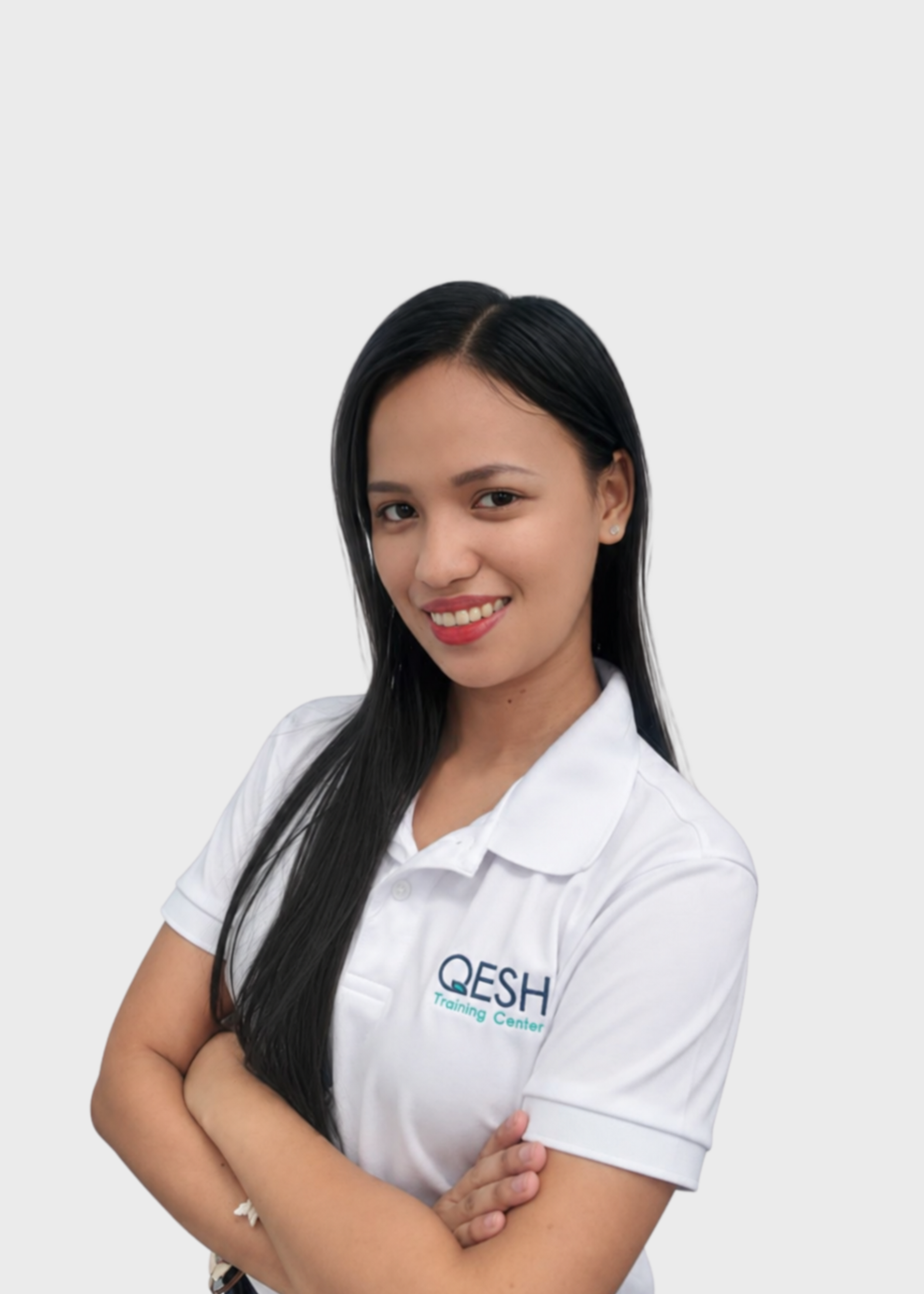 Woman smiling in a white polo shirt with "QESH Training Center" logo, arms crossed, wearing a lanyard.