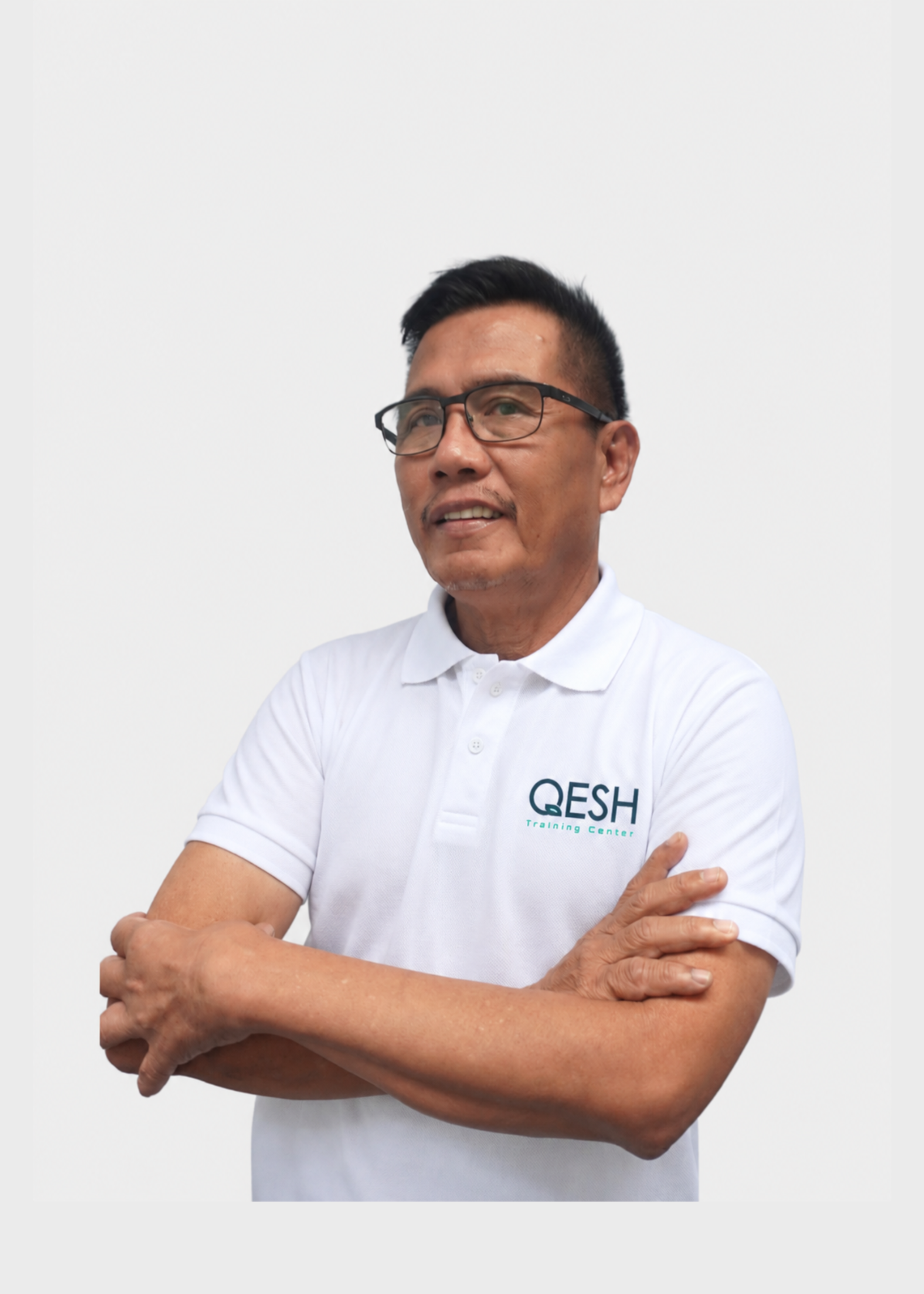 Man wearing glasses and a QESH Training Center polo shirt, standing with arms crossed.