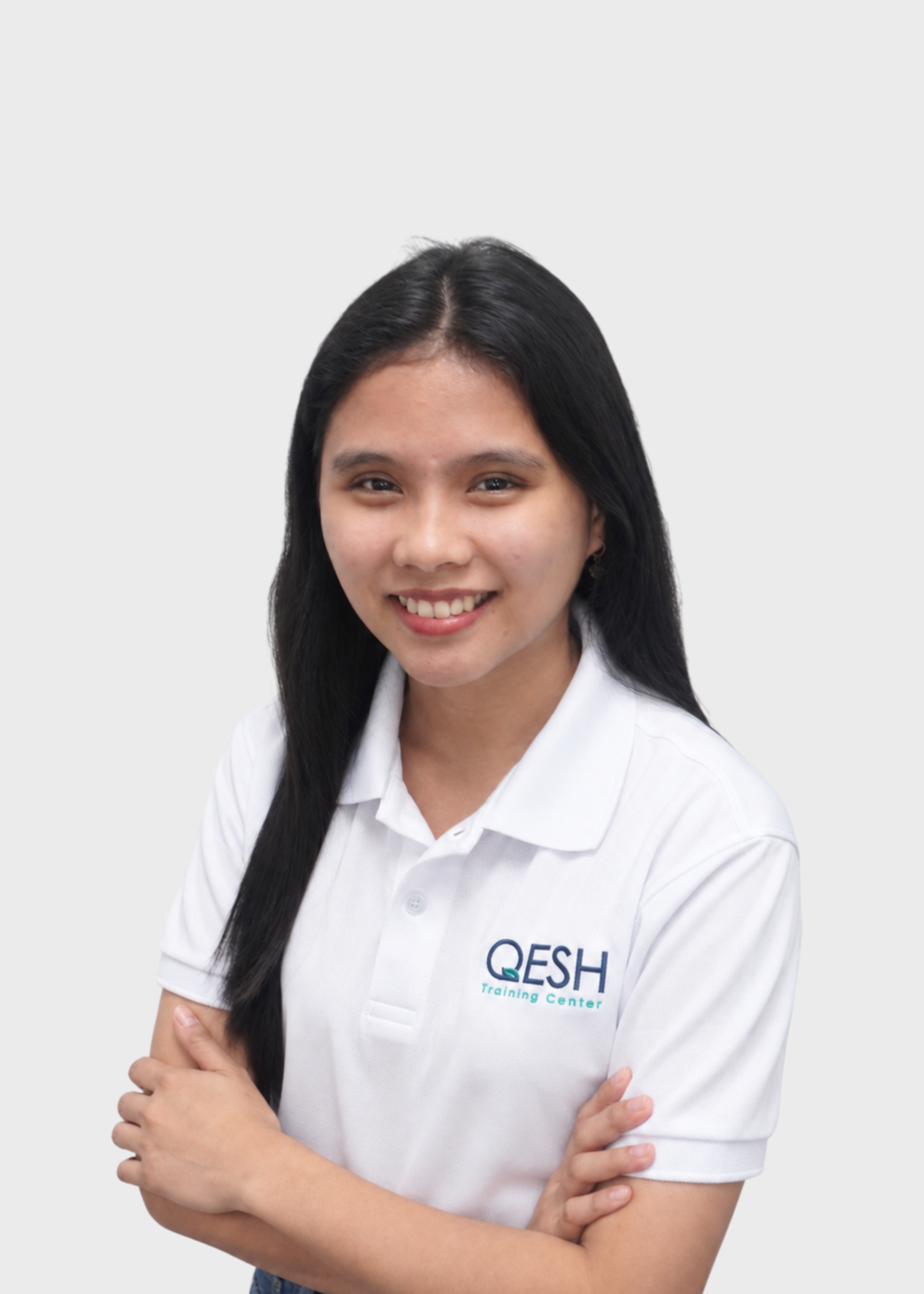 Smiling person in a QESH polo shirt with crossed arms.