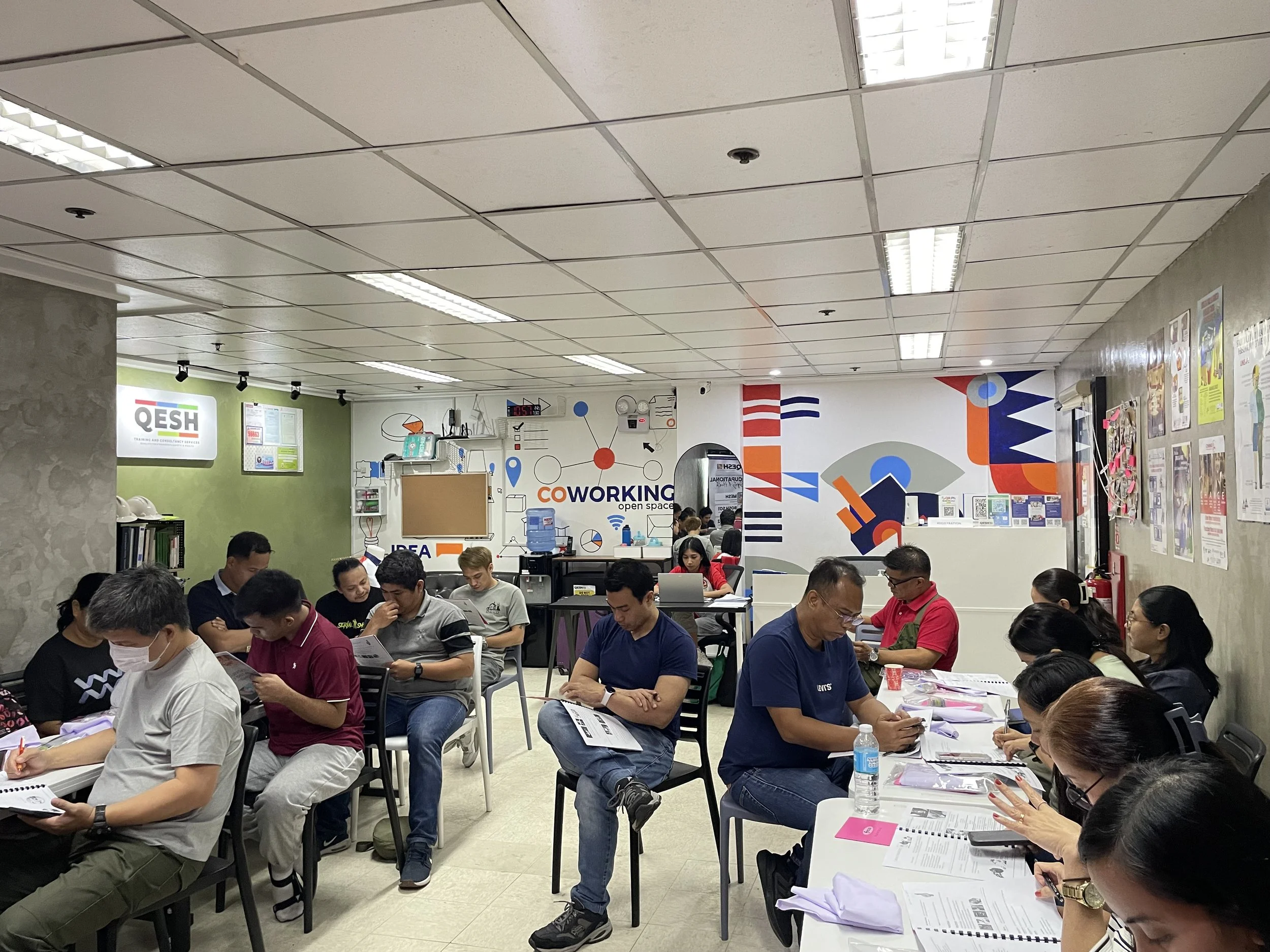 People sitting at tables in a co-working space, engaged in paperwork and discussions.