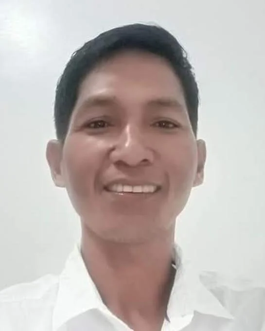 A smiling person wearing a white shirt against a plain background.