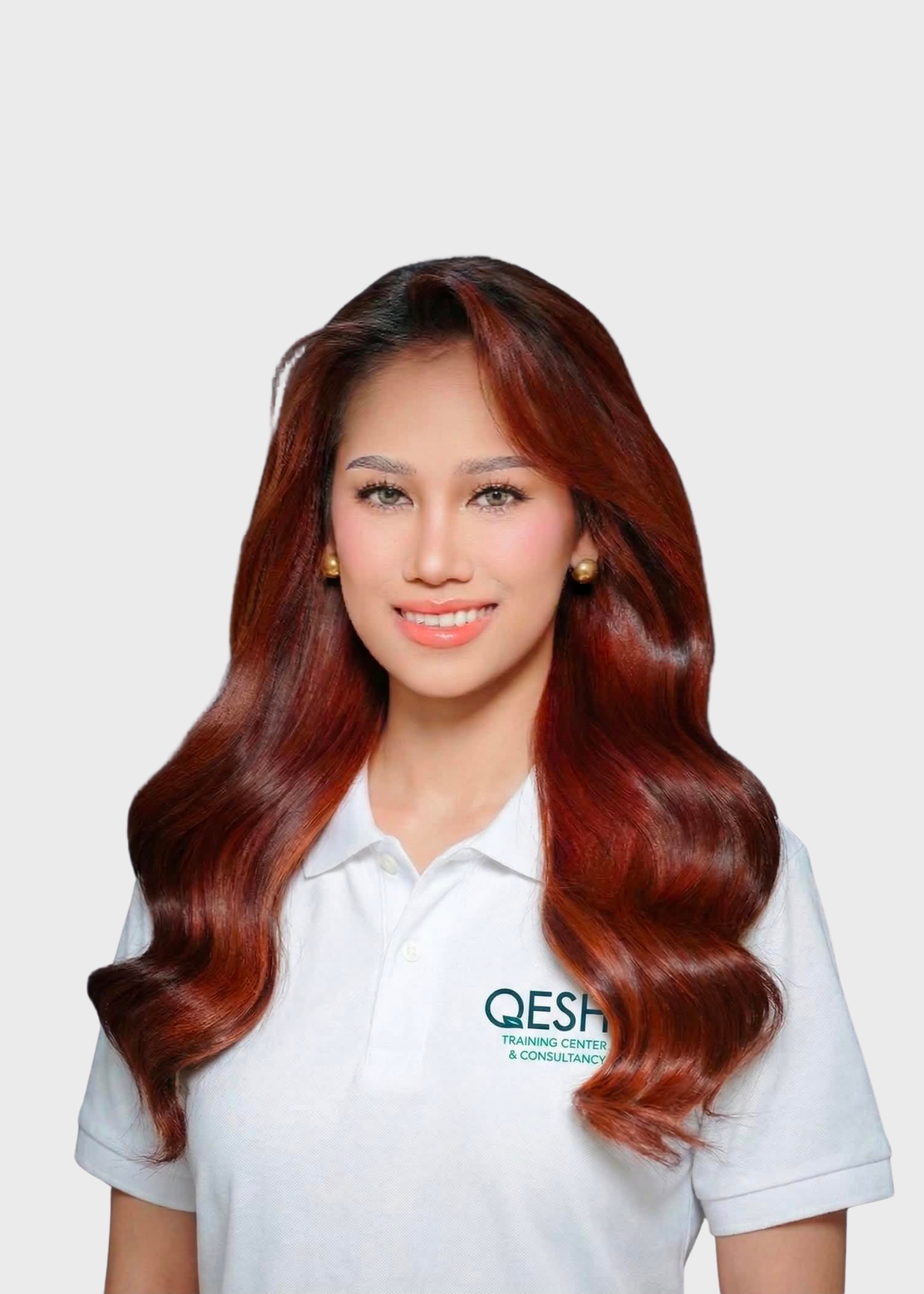 Person wearing a white polo shirt with 'QESH Training Center' logo, smiling with folded arms against a light gray background.