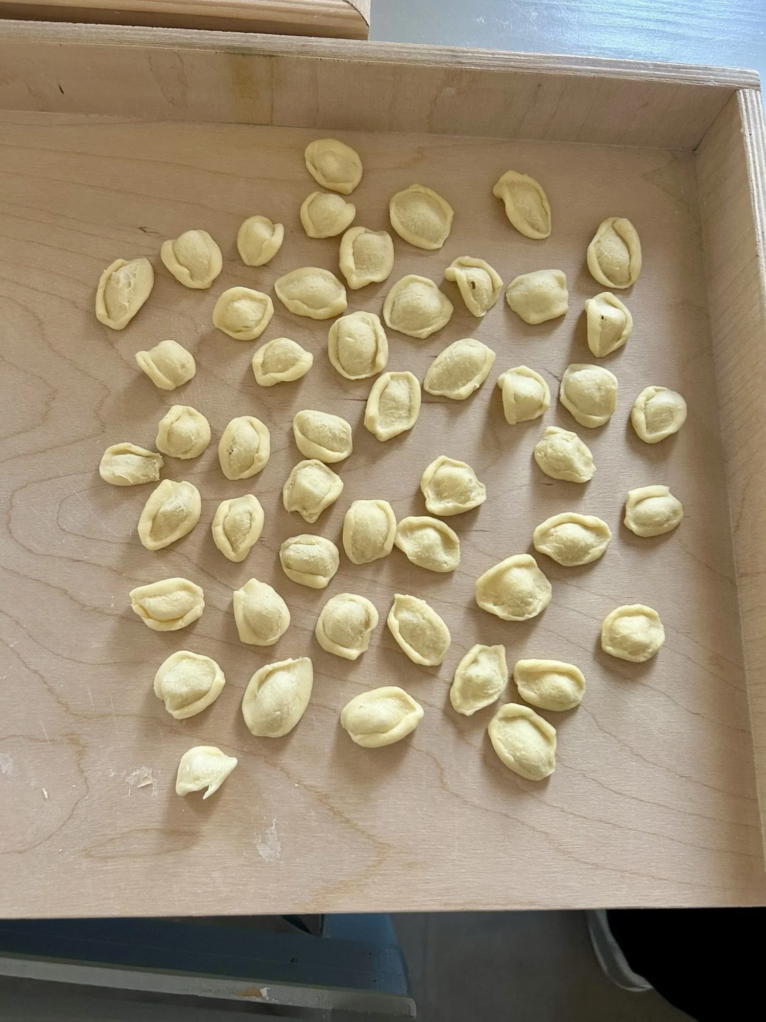 Rows of freshly made orecchiette laid out to dry on a wooden tray in Puglia