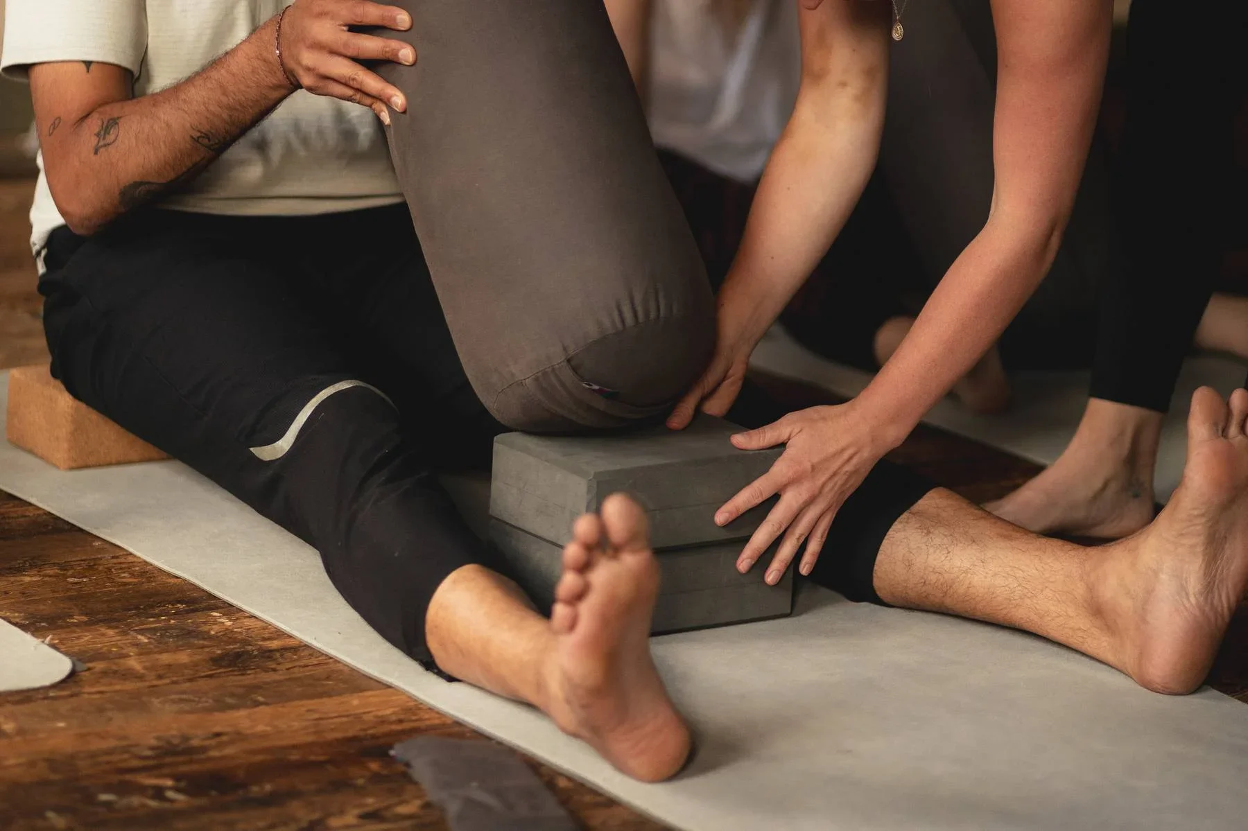 Yoga teacher supporting a student with bolster and blocks during a restorative yoga posture at Heist House Studios in Warwick.