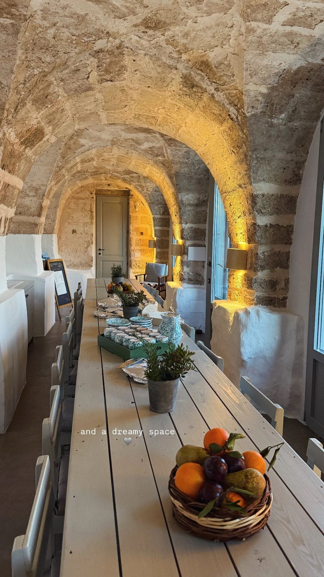 Vaulted stone archways running the length of the dining room at Masseria Specula, with a long table laid for the retreat group