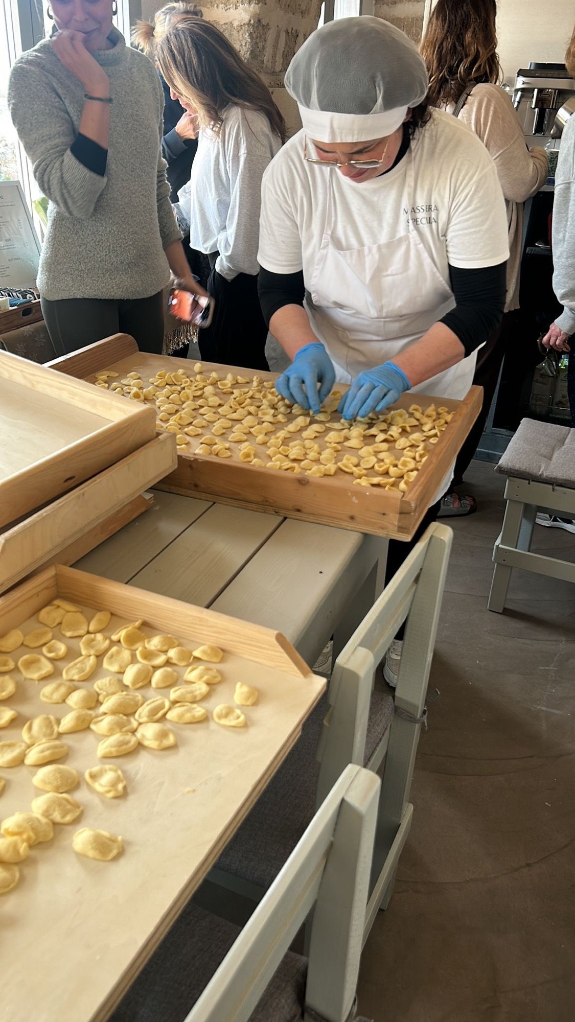 Orecchiette being shaped by hand and pressed onto wooden trays while retreat guests watch