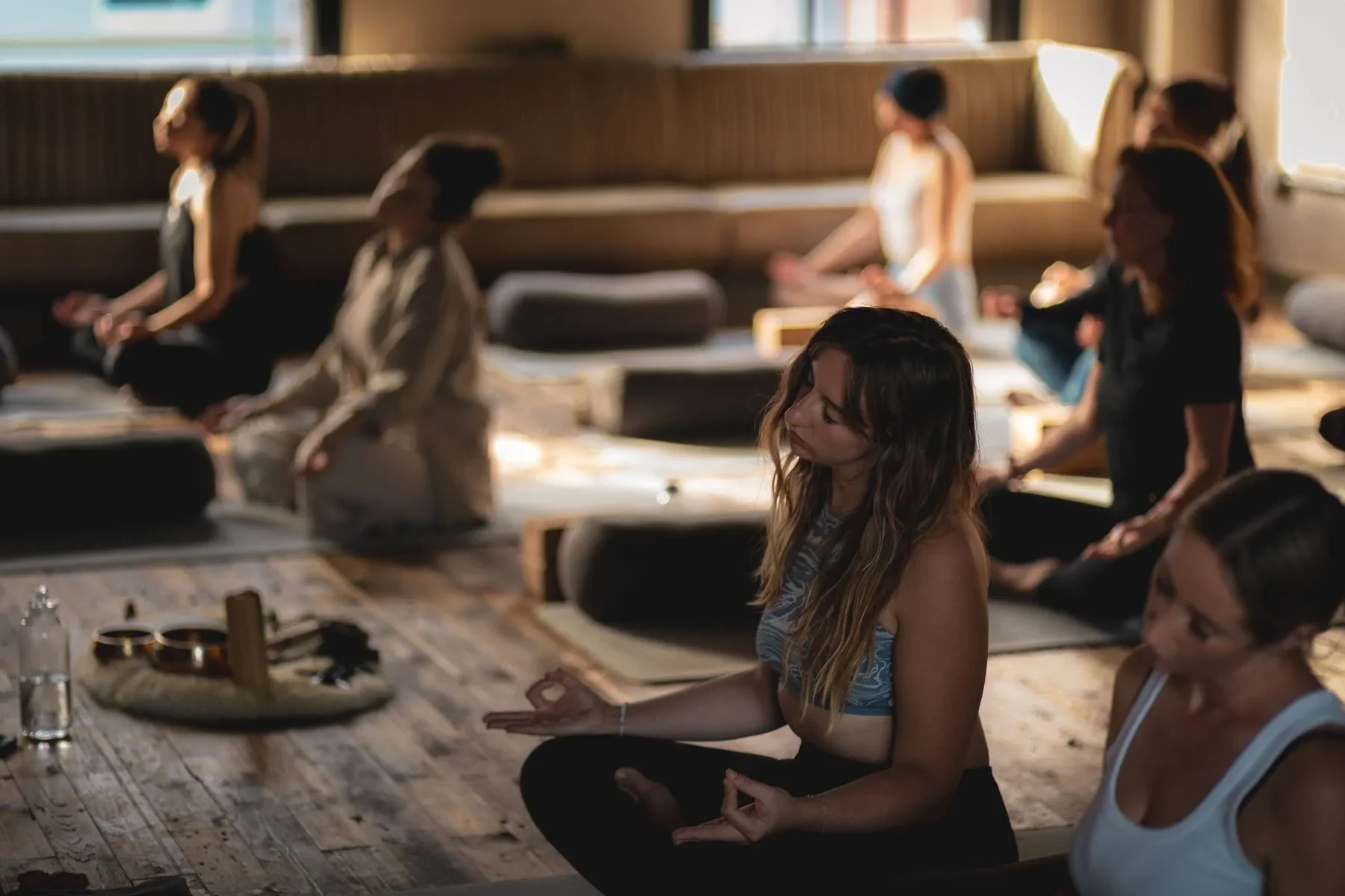 Group meditation and sound healing session at Heist House Studios in Warwick — students seated on mats with singing bowls in the foreground