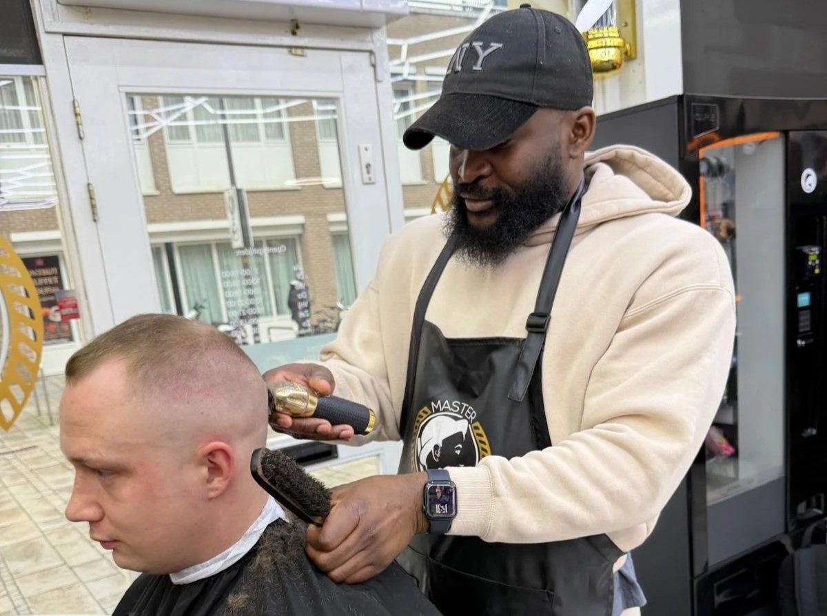 Barber snijdt het haar van een man in een kapperszaak.