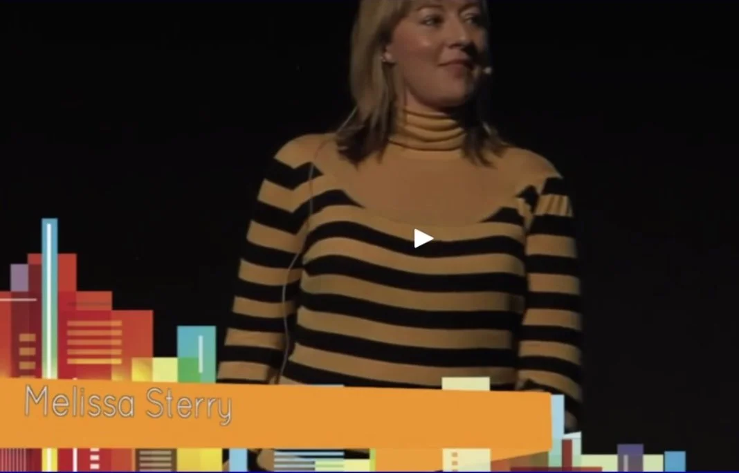 Design scientist and planetary futurist Dr. Melissa Sterry wearing a yellow and black striped shirt on stage with text overlay "Melissa Sterry."