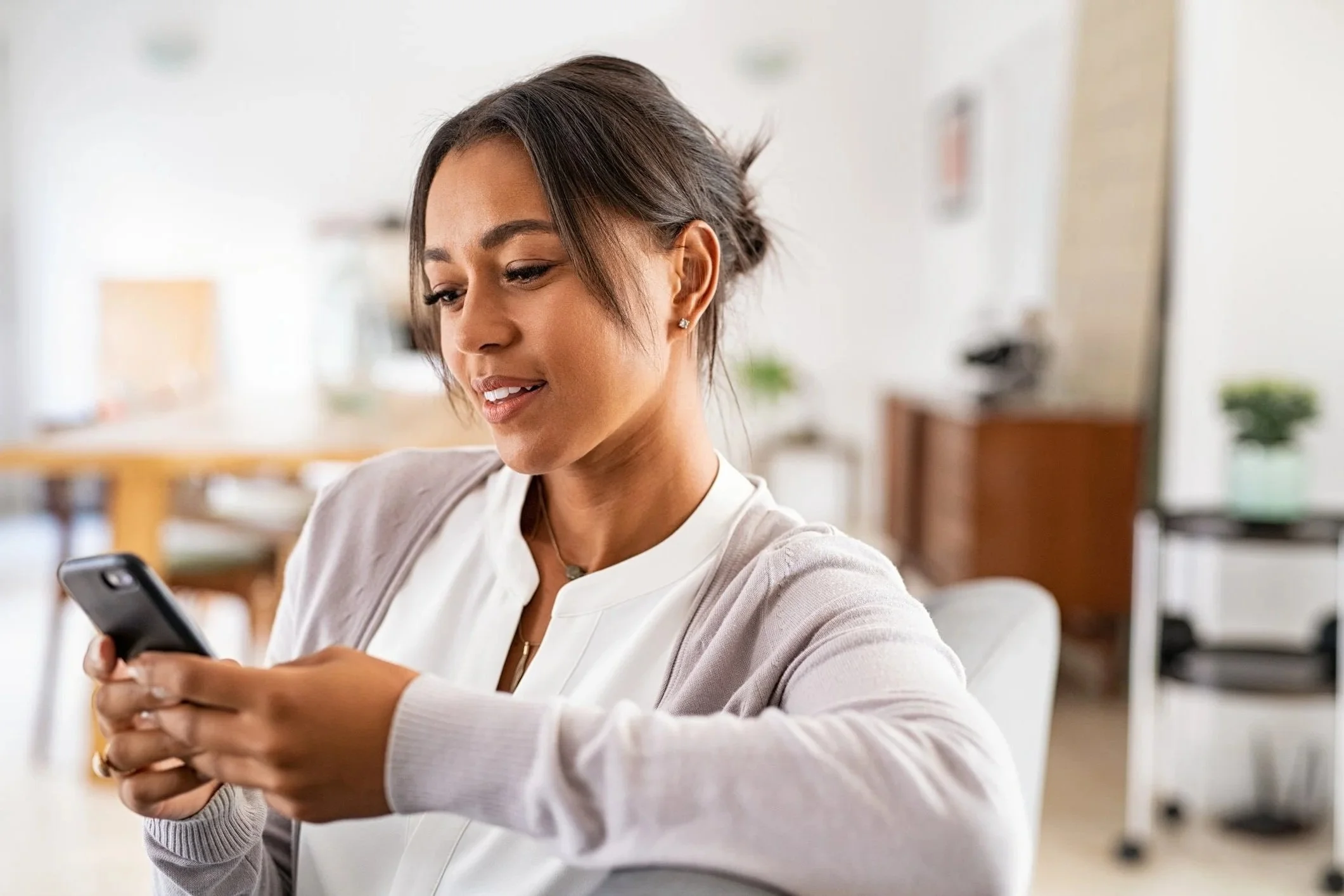 woman of color reading a newsletter on her phone looking pleasantly surprised