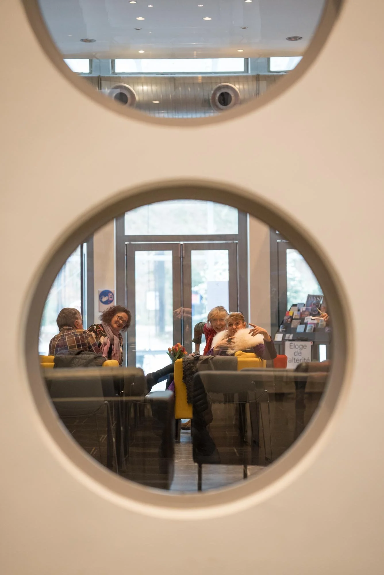 a round window giving a sight on sofas where people are talking