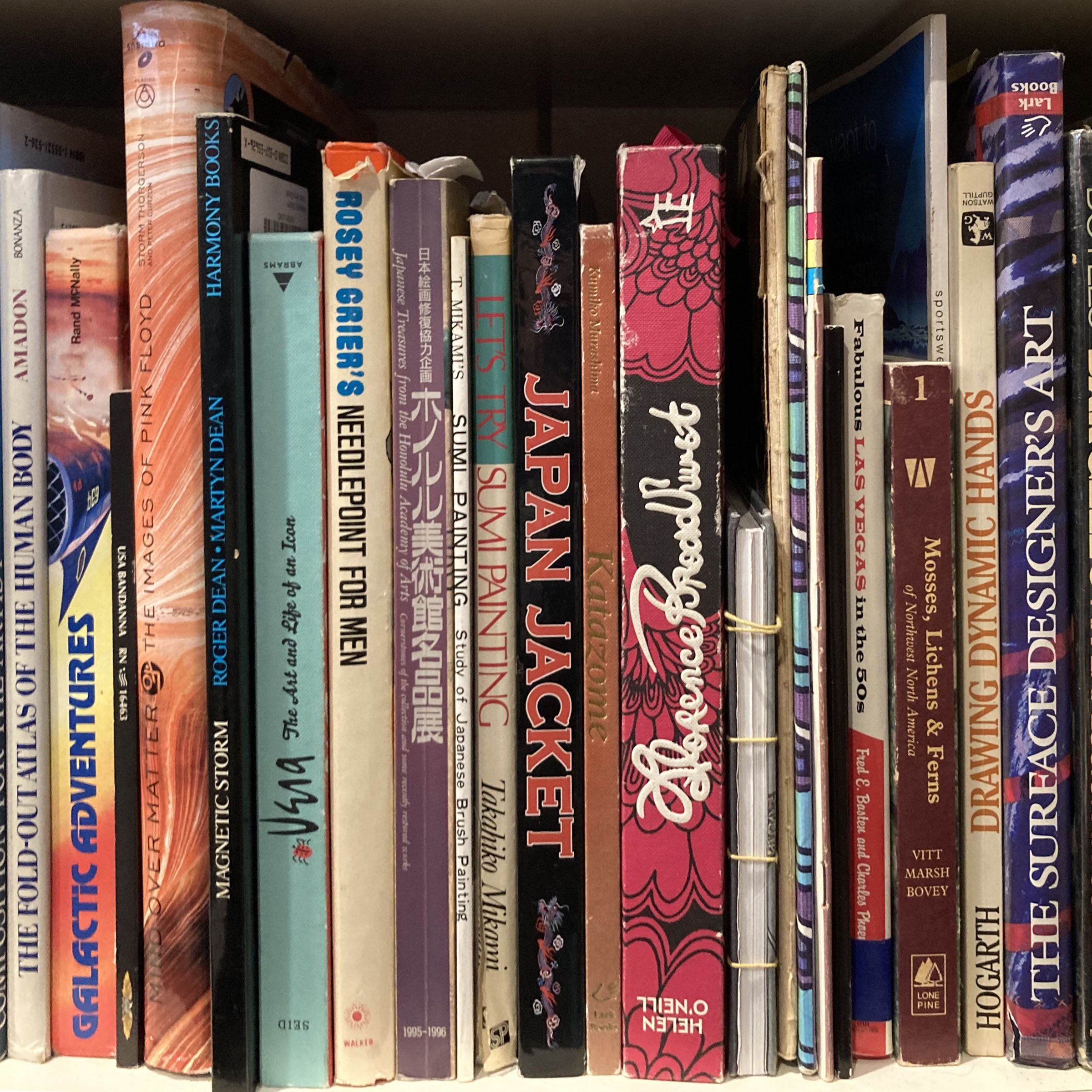 A bookshelf filled with various paperback and hardcover books, with titles partially visible and arranged upright.