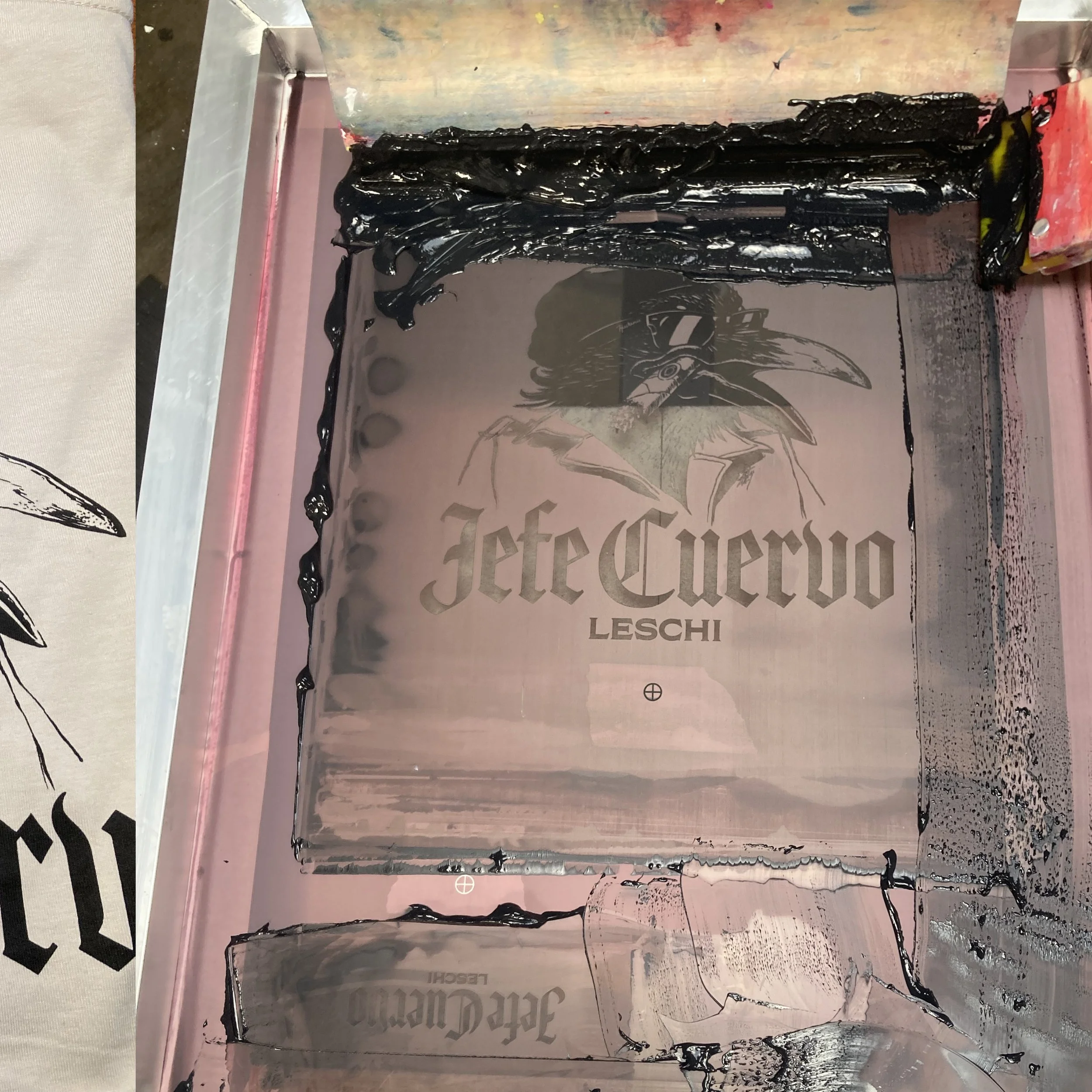 A display of a bar of soap with black melted wax dripped on top, placed on a cardboard box with printed text. The background contains a poster or print featuring a black and white drawing of a figure in a hat and sunglasses.