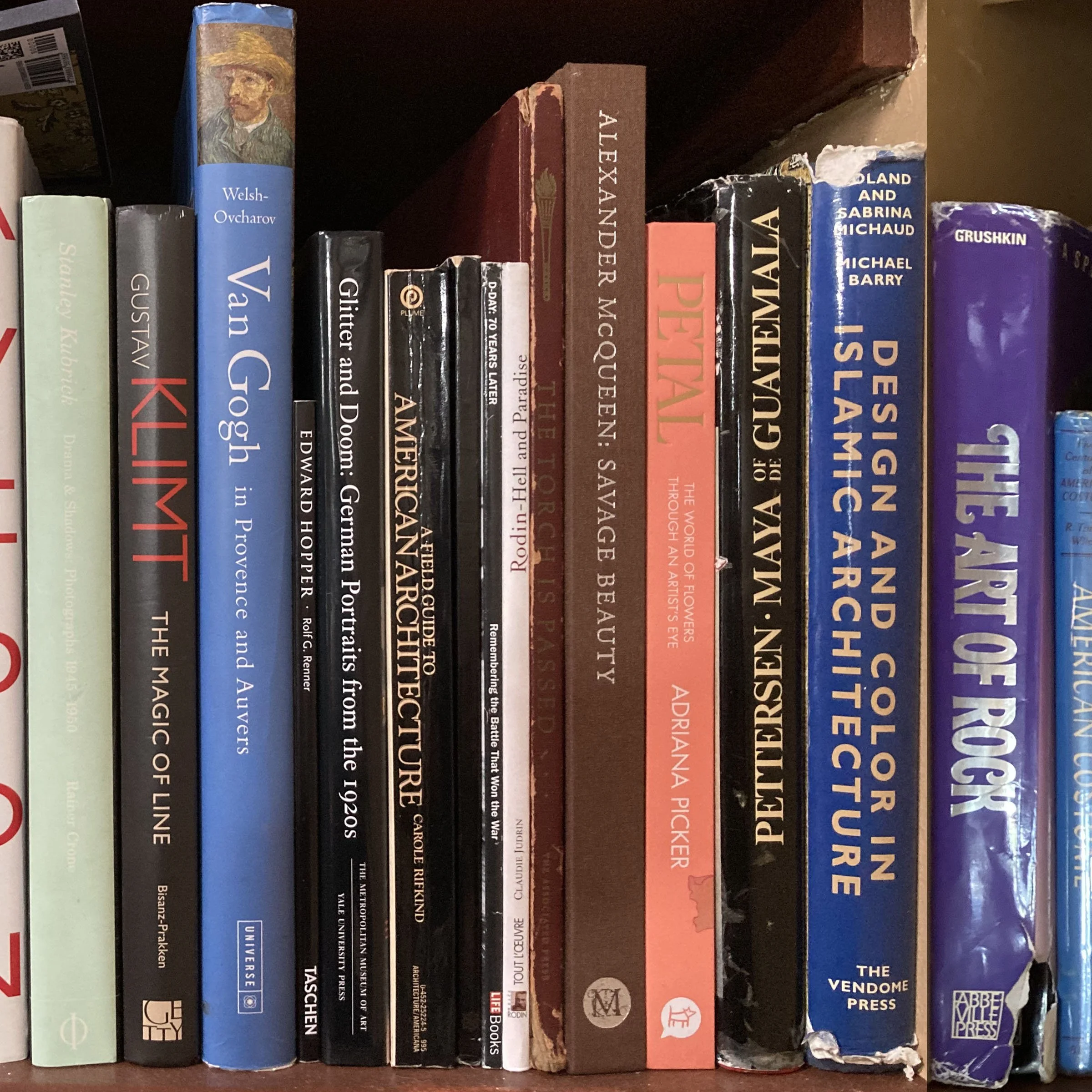 Shelf with various hardcover and paperback books, some titles visible including works by Welsh-Ovcharov, Van Gaalen, Greiman, and others, with a notable tattered blue book featuring a portrait of a woman in a straw hat.