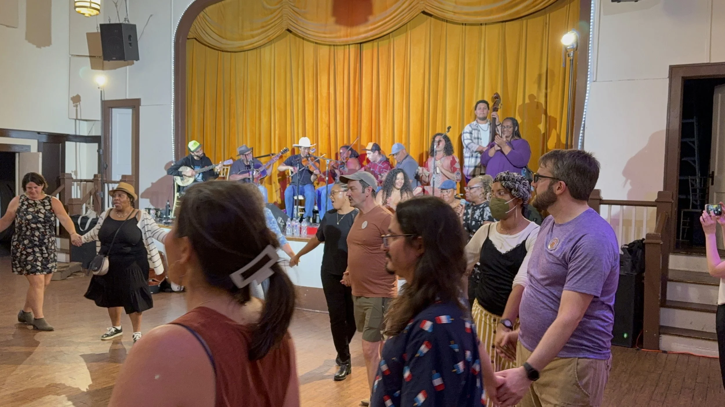 AA Dance Caller Pathways cohort member Carol July calls a dance at the FWAAMFest free Friday kickoff event, accompanied by a live band.