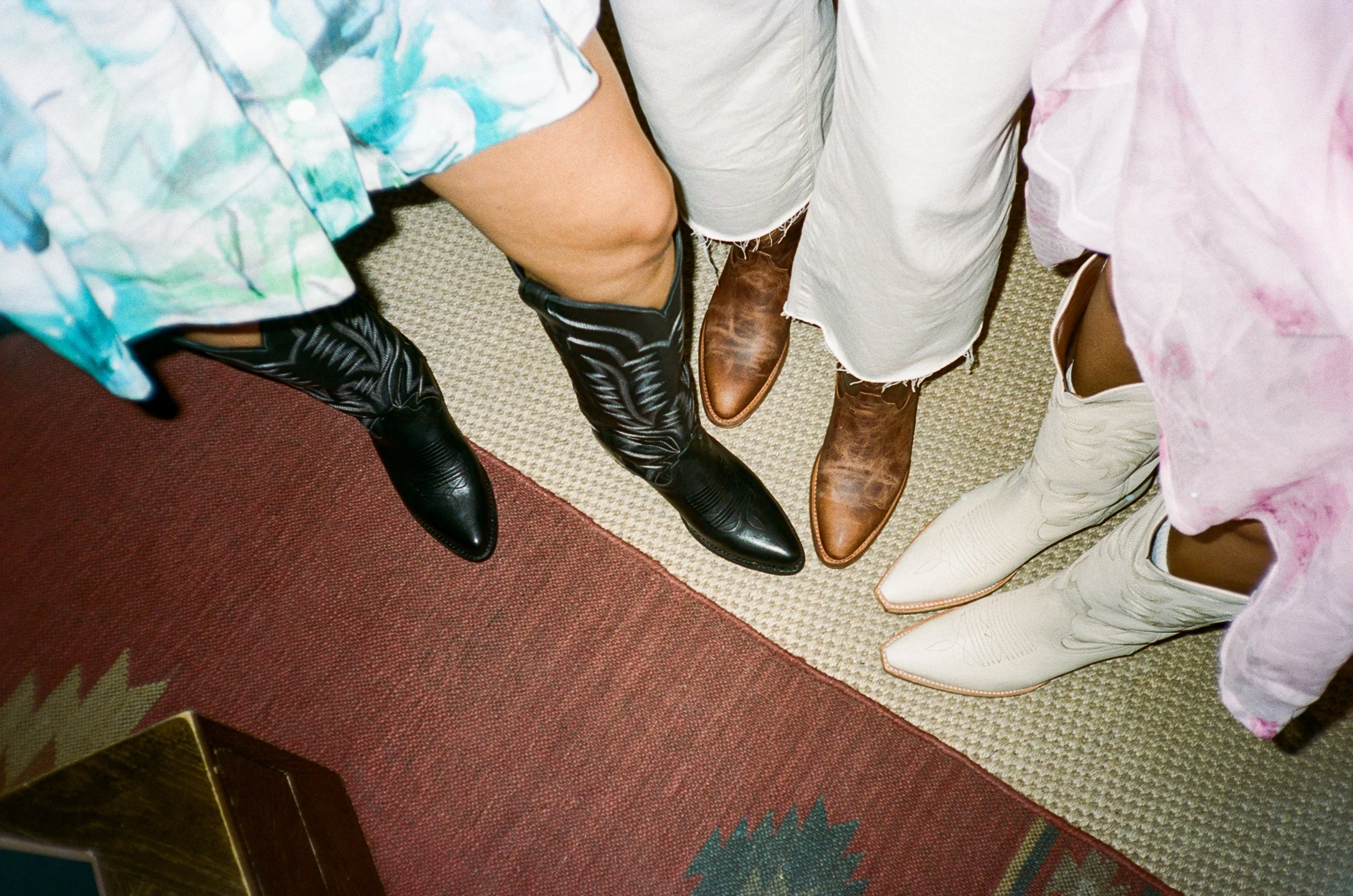 People wearing cowboy boots in various colors standing in a circle.